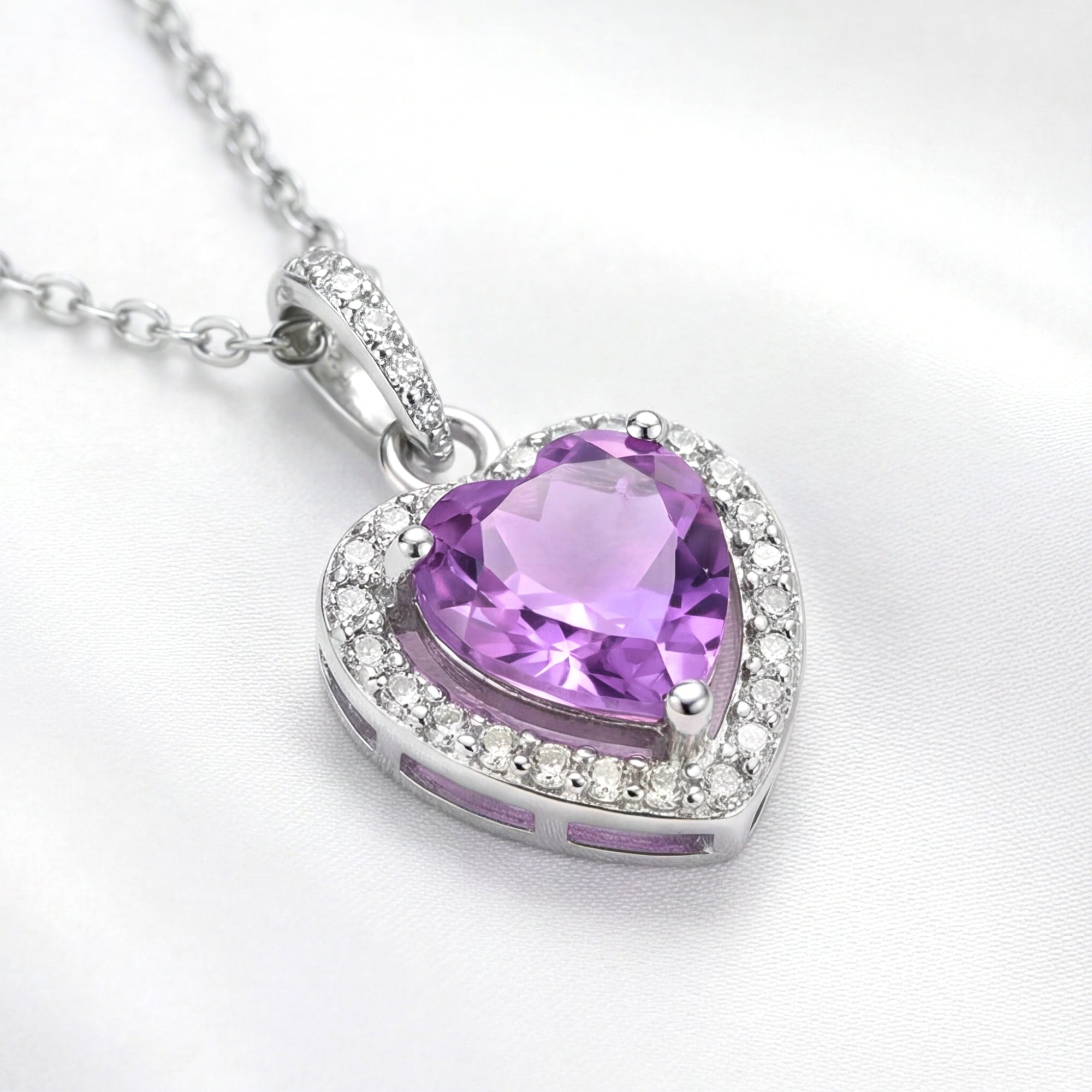 Heart-cut simulated amethyst necklace in S925 sterling silver with a halo setting on a white silk background.