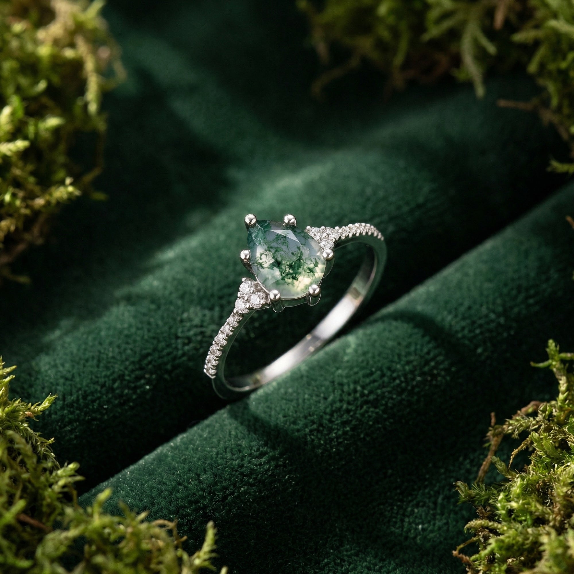 Pear cut moss agate ring in S925 sterling silver on green velvet surrounded by natural moss.