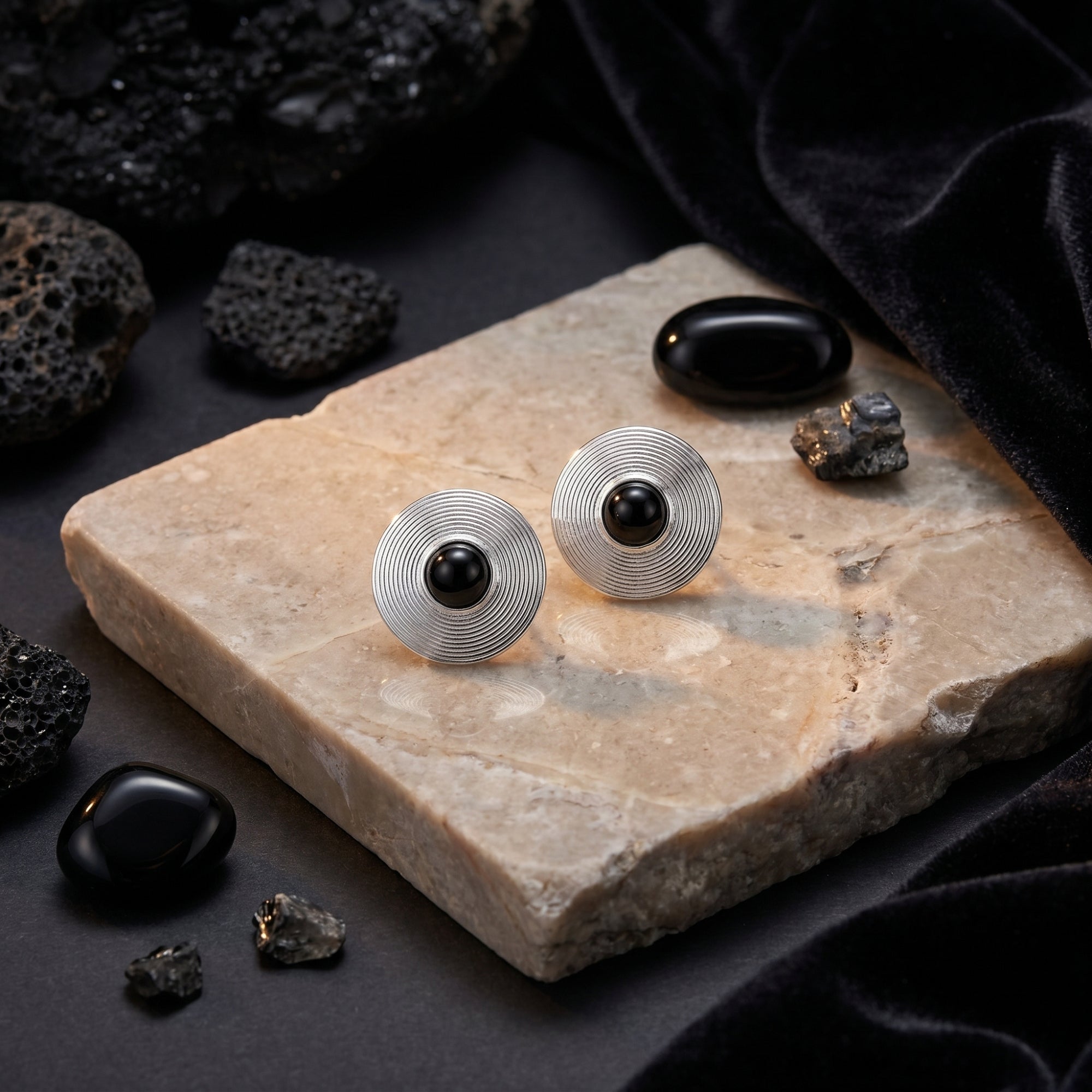 Silver Architect stud earrings with round black onyx on a stone slab with velvet and volcanic rocks.