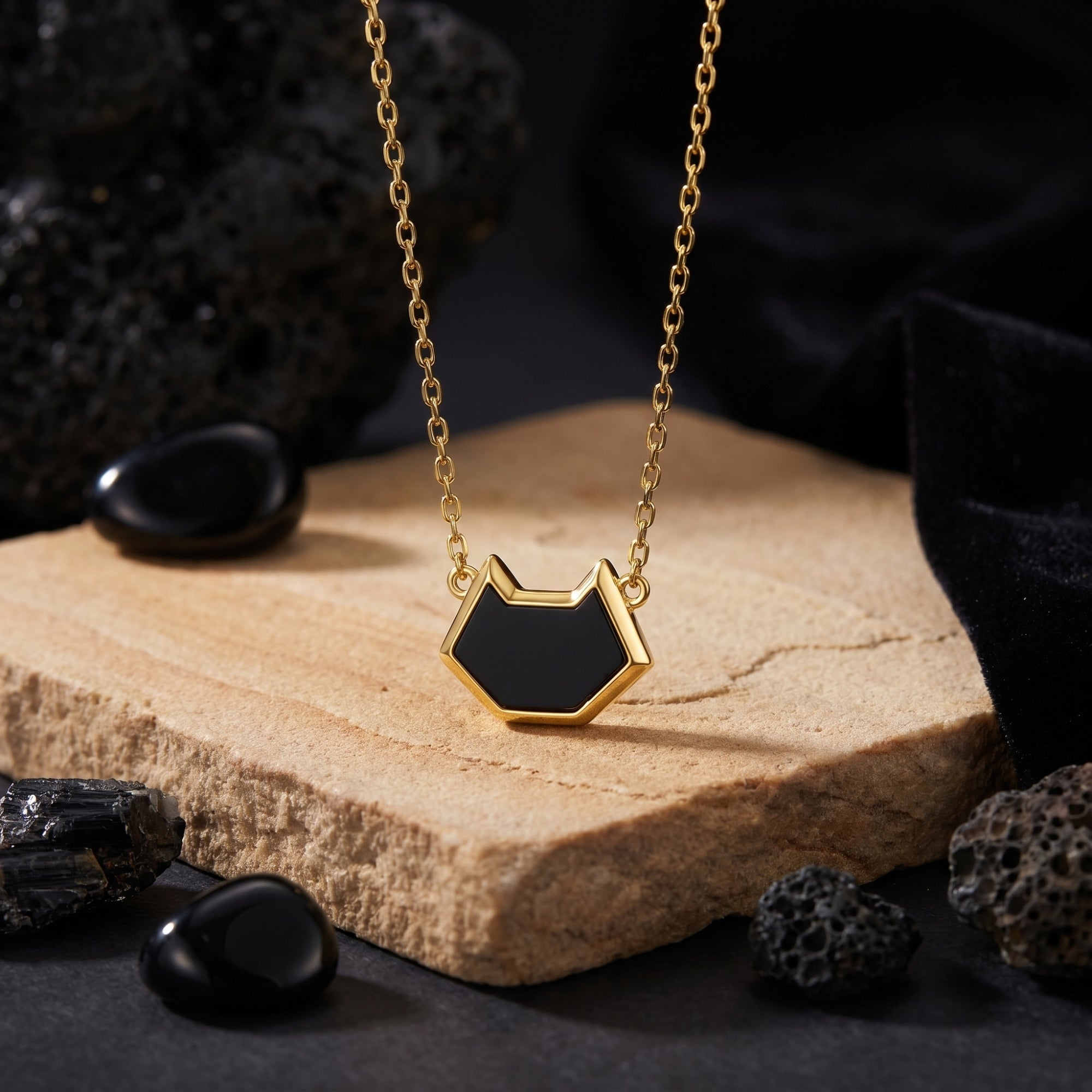 Irregular-cut black onyx pendant on an 18K gold plated chain, styled with volcanic rocks and a stone block.