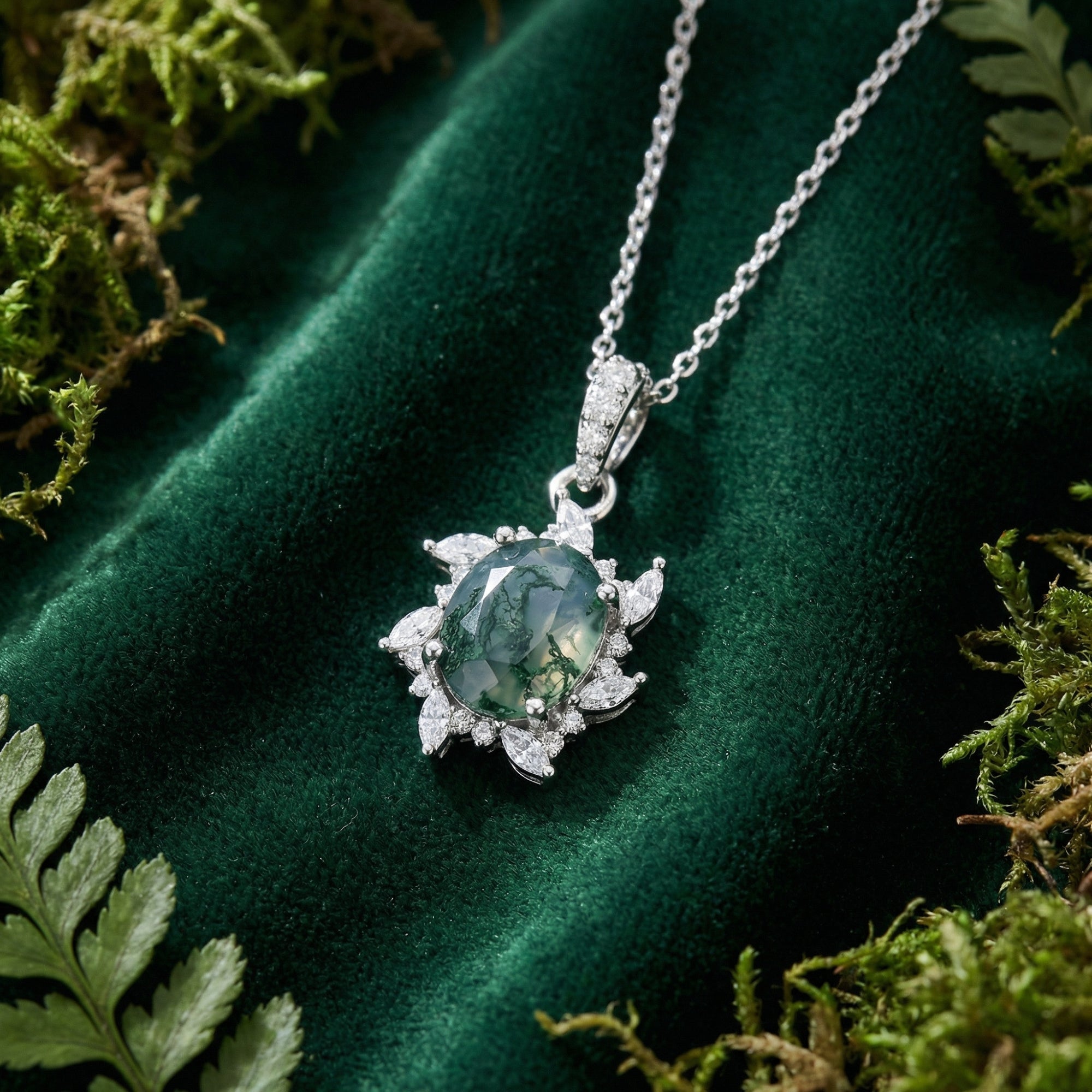 Starburst moss agate pendant necklace in S925 sterling silver on green velvet with natural moss accents.