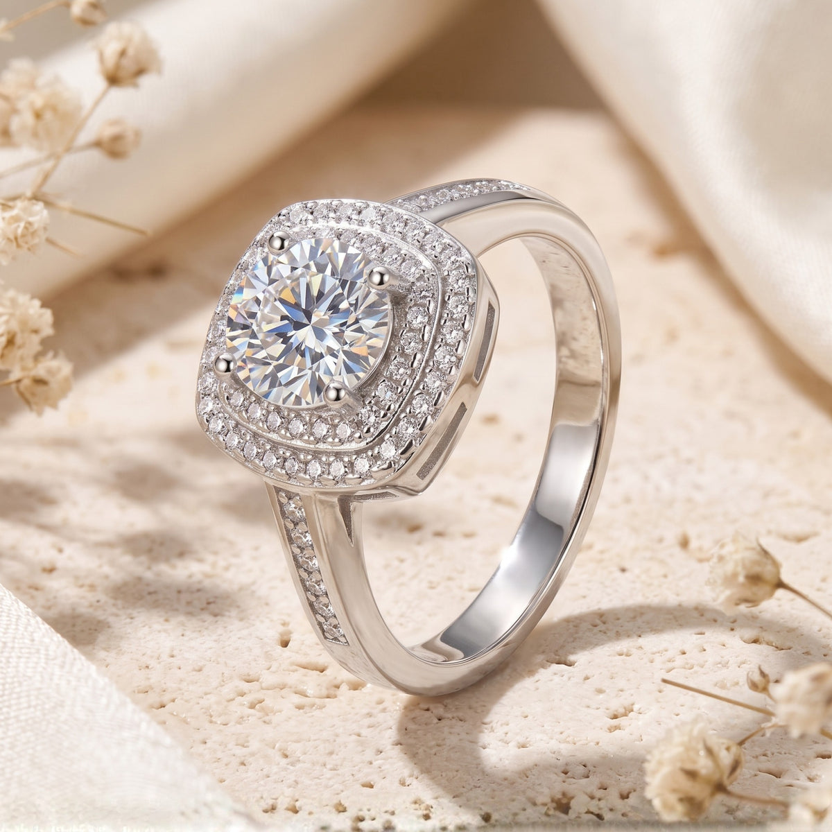 Angled close-up of a silver ring with a round center gem enclosed by a cushion-shaped double halo.