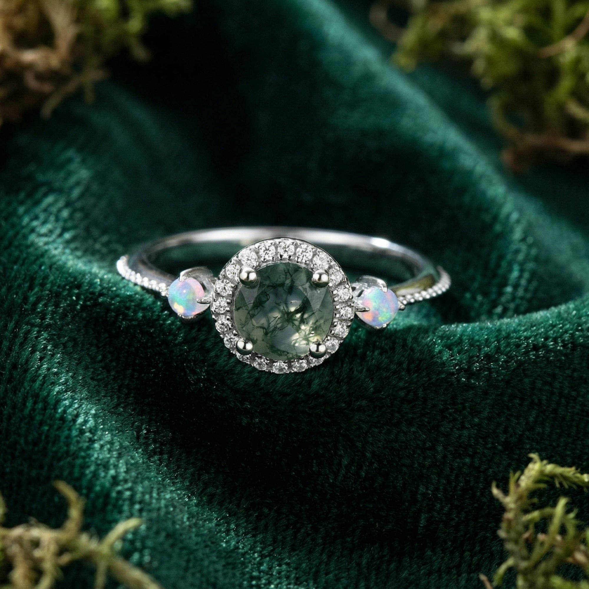 Round cut moss agate halo ring with opalescent side stones in S925 sterling silver on green velvet.