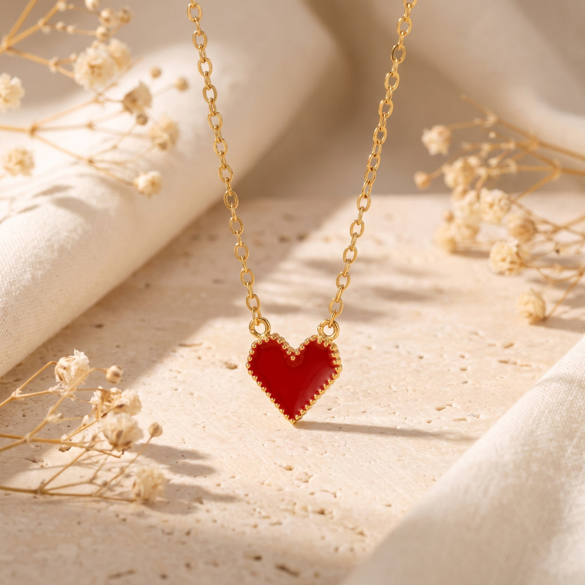 Close-up of the red heart pendant with a beaded gold-tone border hanging from its chain.