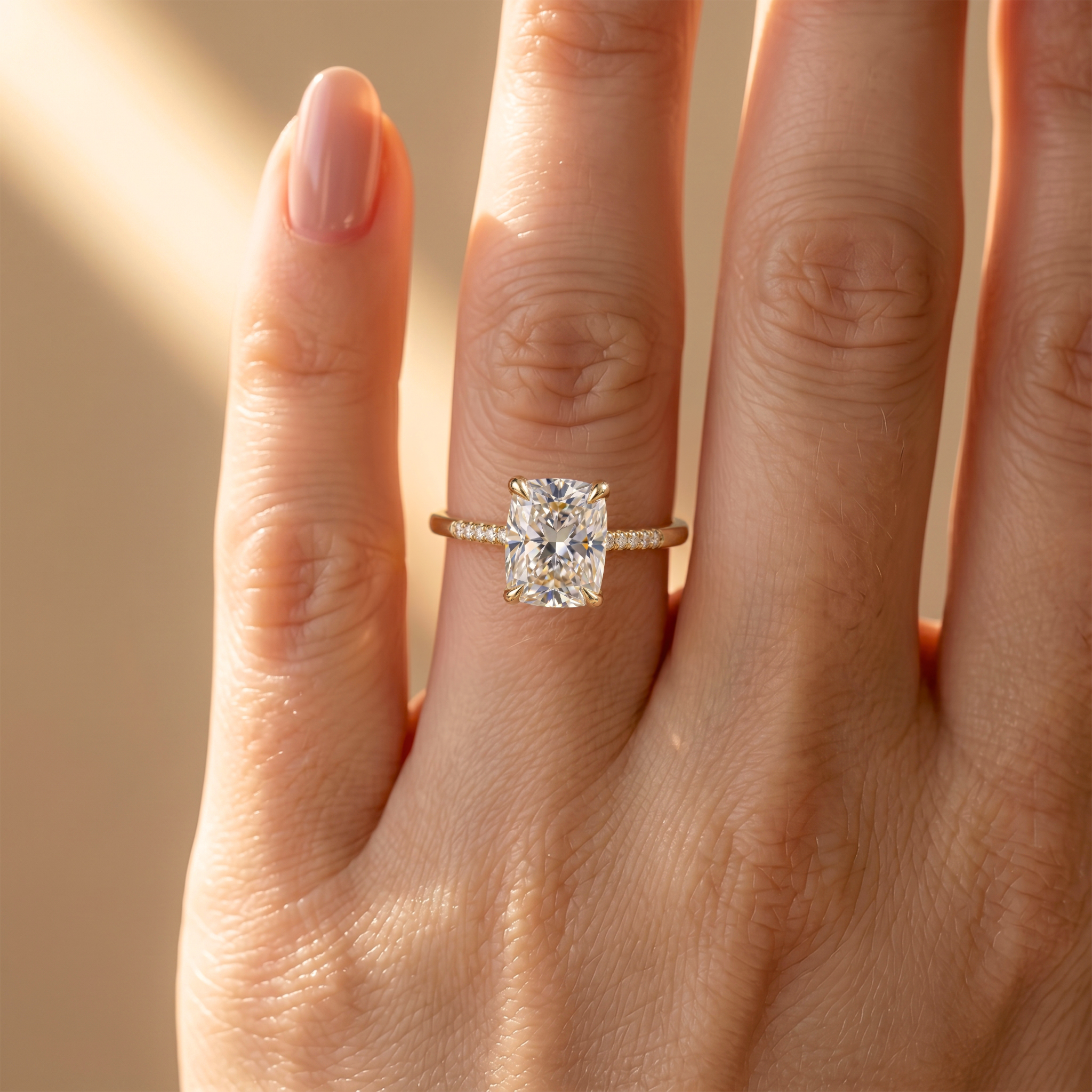 A close-up view of a gold cushion-cut moissanite ring with a sparkling pave band worn on a finger.