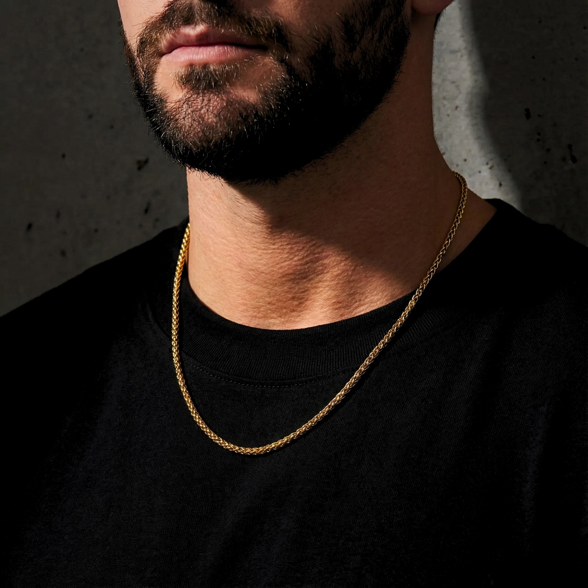 Man wearing a gold stainless steel wheat chain necklace over a black t-shirt.