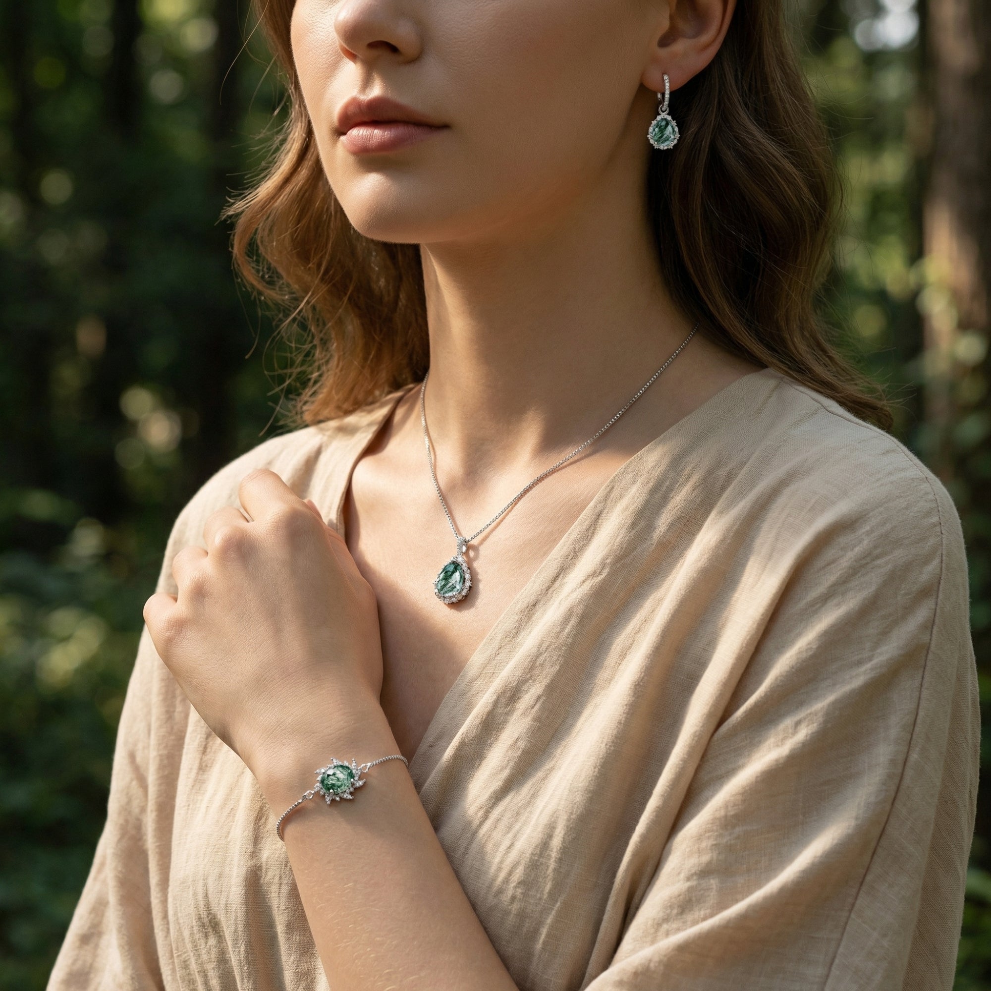 Model wearing the sterling silver Moss Agate necklace, drop earrings, and adjustable bracelet in a forest setting.