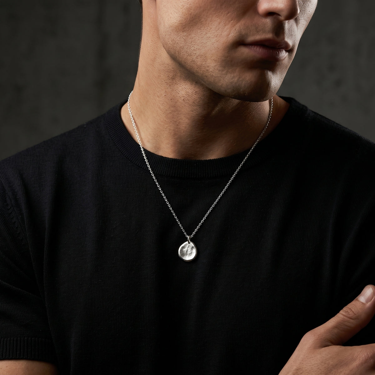Model wearing the silver textured pebble pendant necklace over a black crewneck T-shirt.