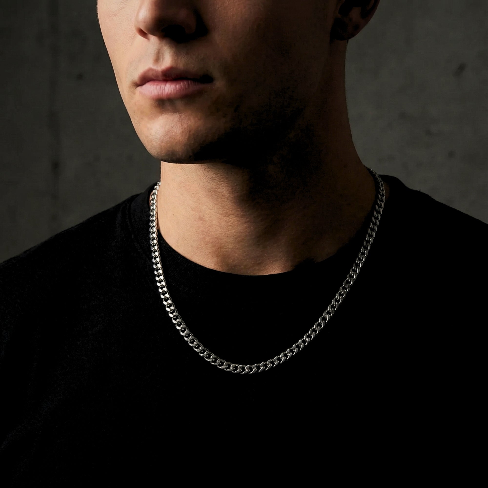 Silver 4mm stainless steel Cuban link chain worn by a man over a black t-shirt.