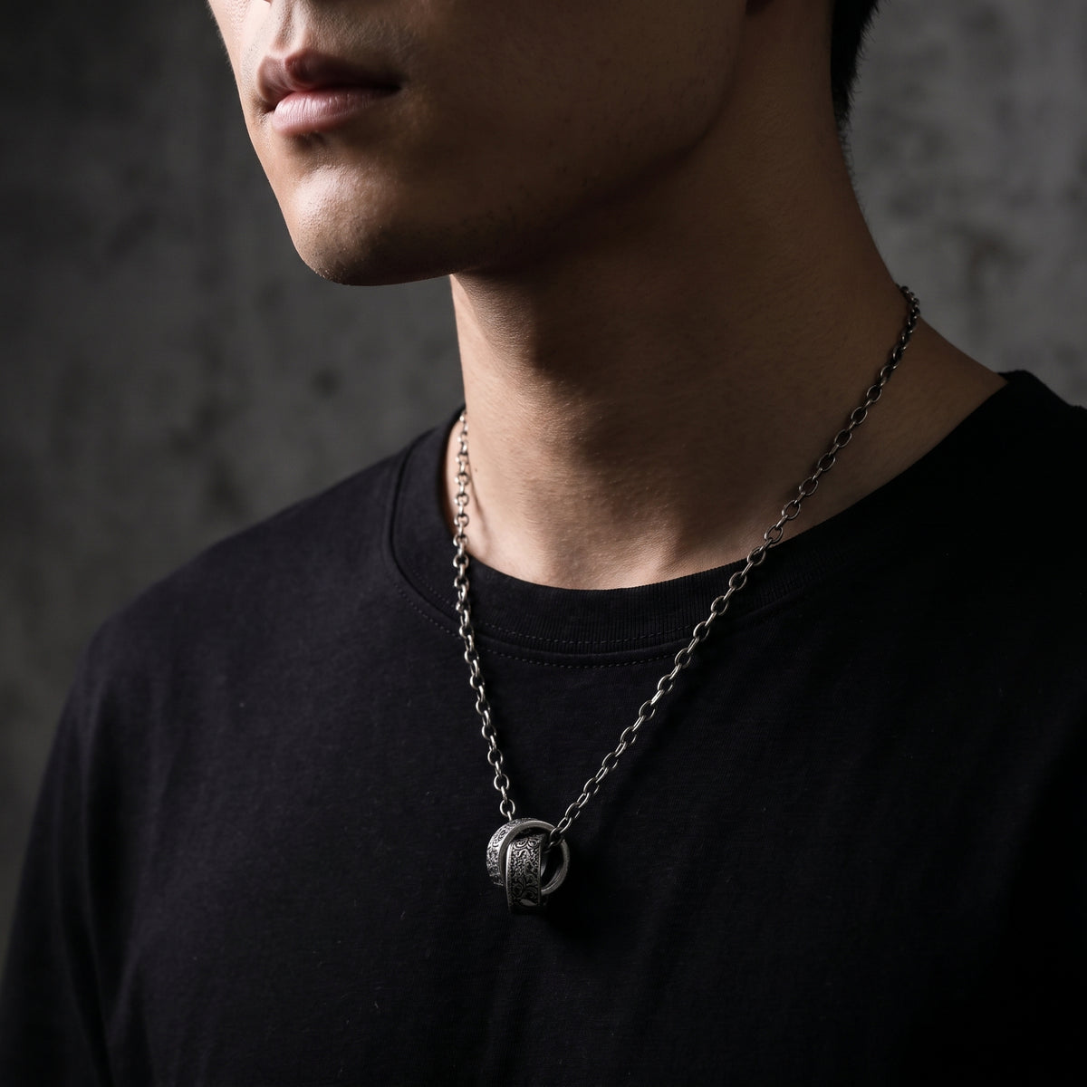 Man wearing the silver dual-ring pendant necklace over a simple black T-shirt.