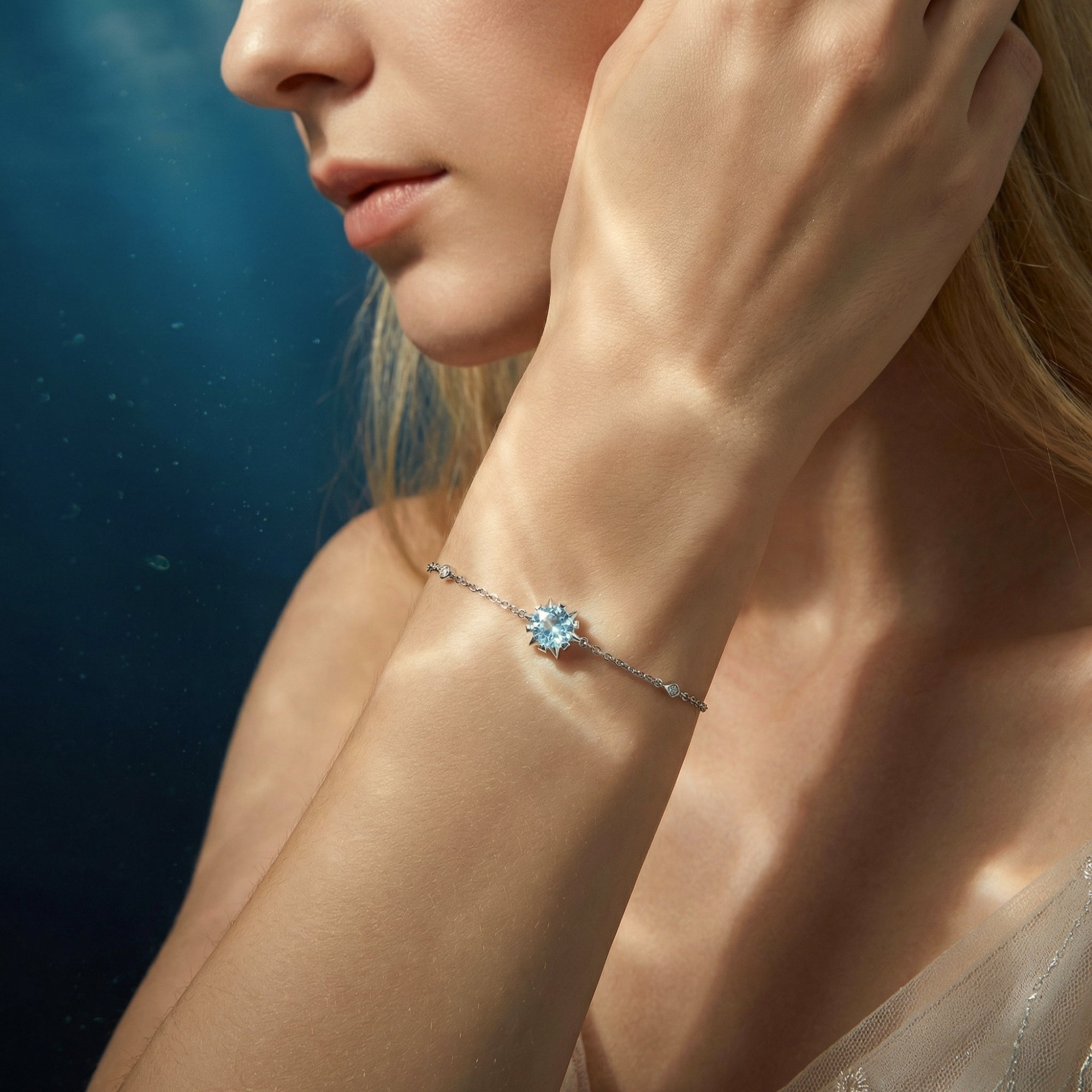 Stellamira platinum station bracelet with a round natural aquamarine worn on a woman's wrist.
