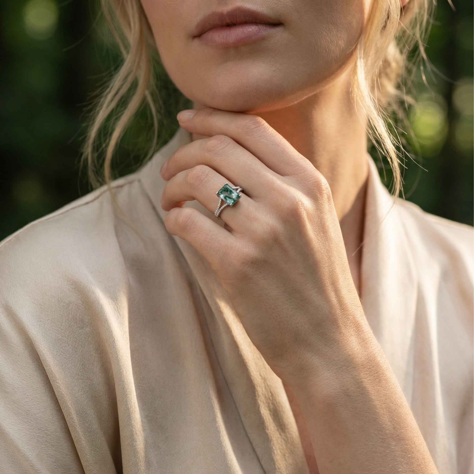 Model wearing a cushion cut moss agate sterling silver ring on her finger in a natural outdoor setting.