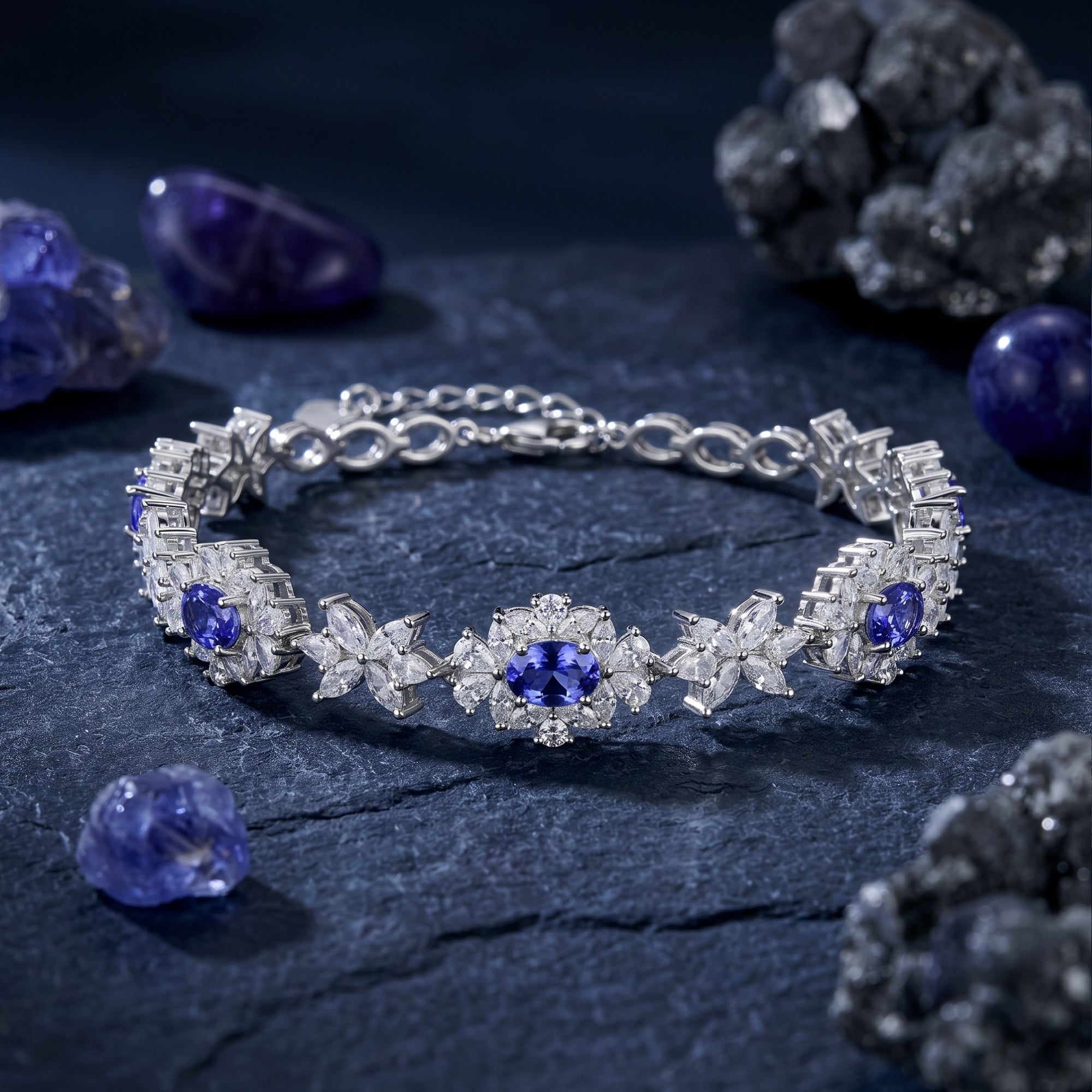 Macro view of oval cut blue tanzanite stones in a floral white gold tennis bracelet setting.