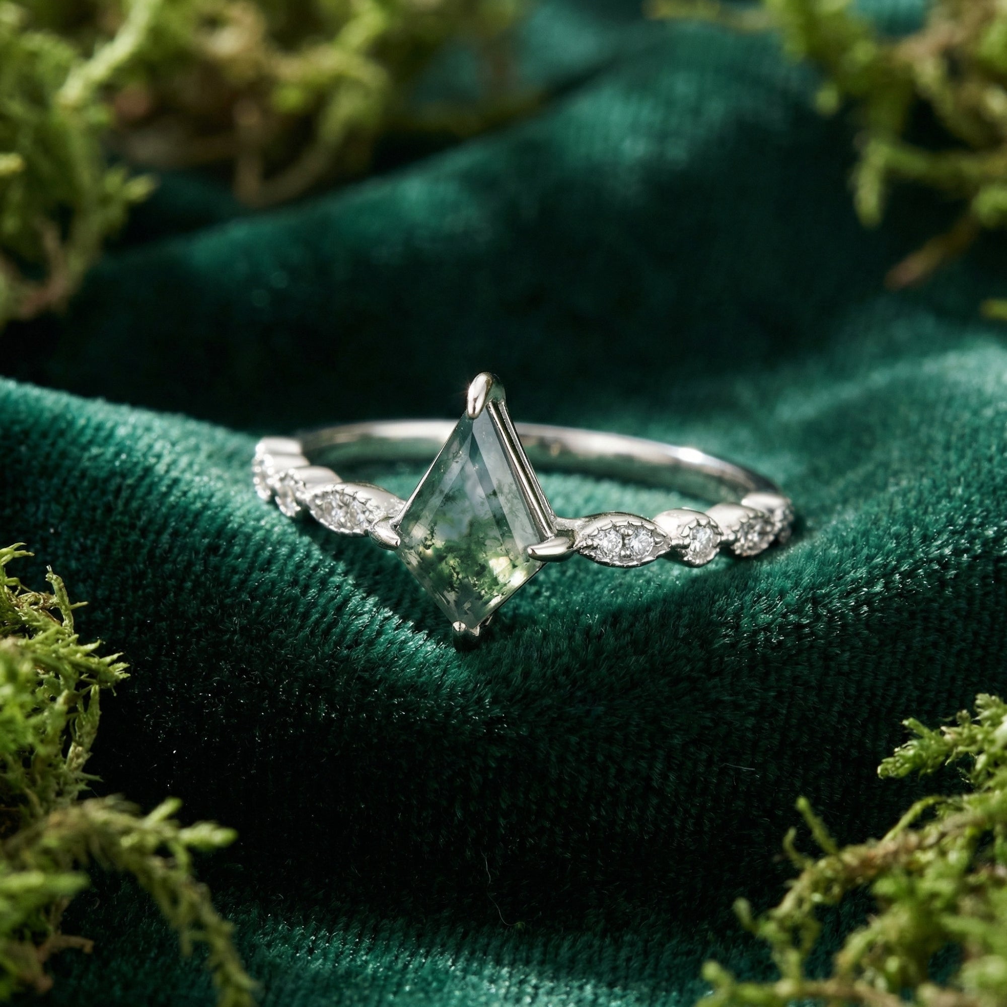 Detailed view of a kite cut moss agate stone and diamond-accented S925 sterling silver band on green velvet.
