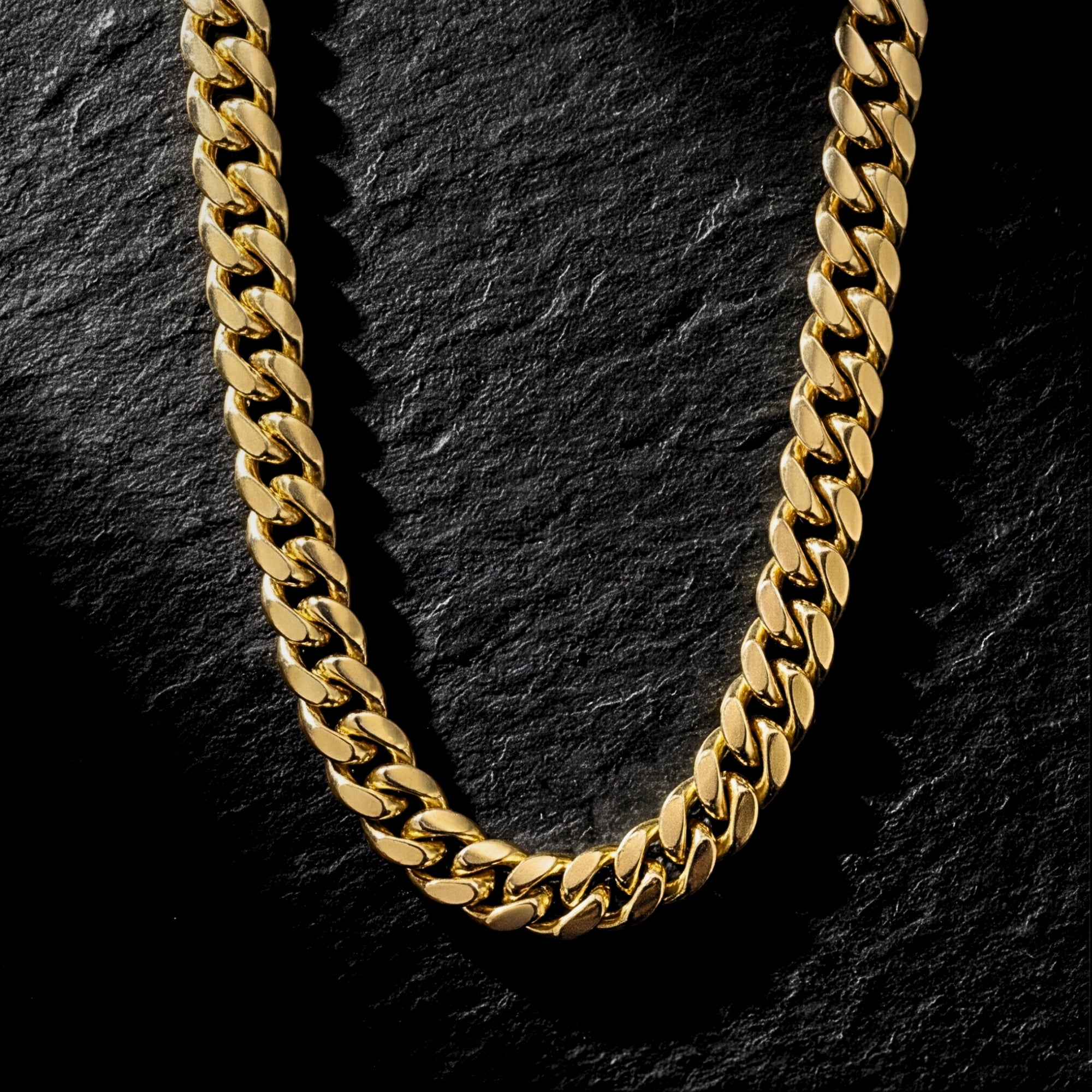 Top-down view of a 6mm gold Cuban link chain in stainless steel on a dark slate background.