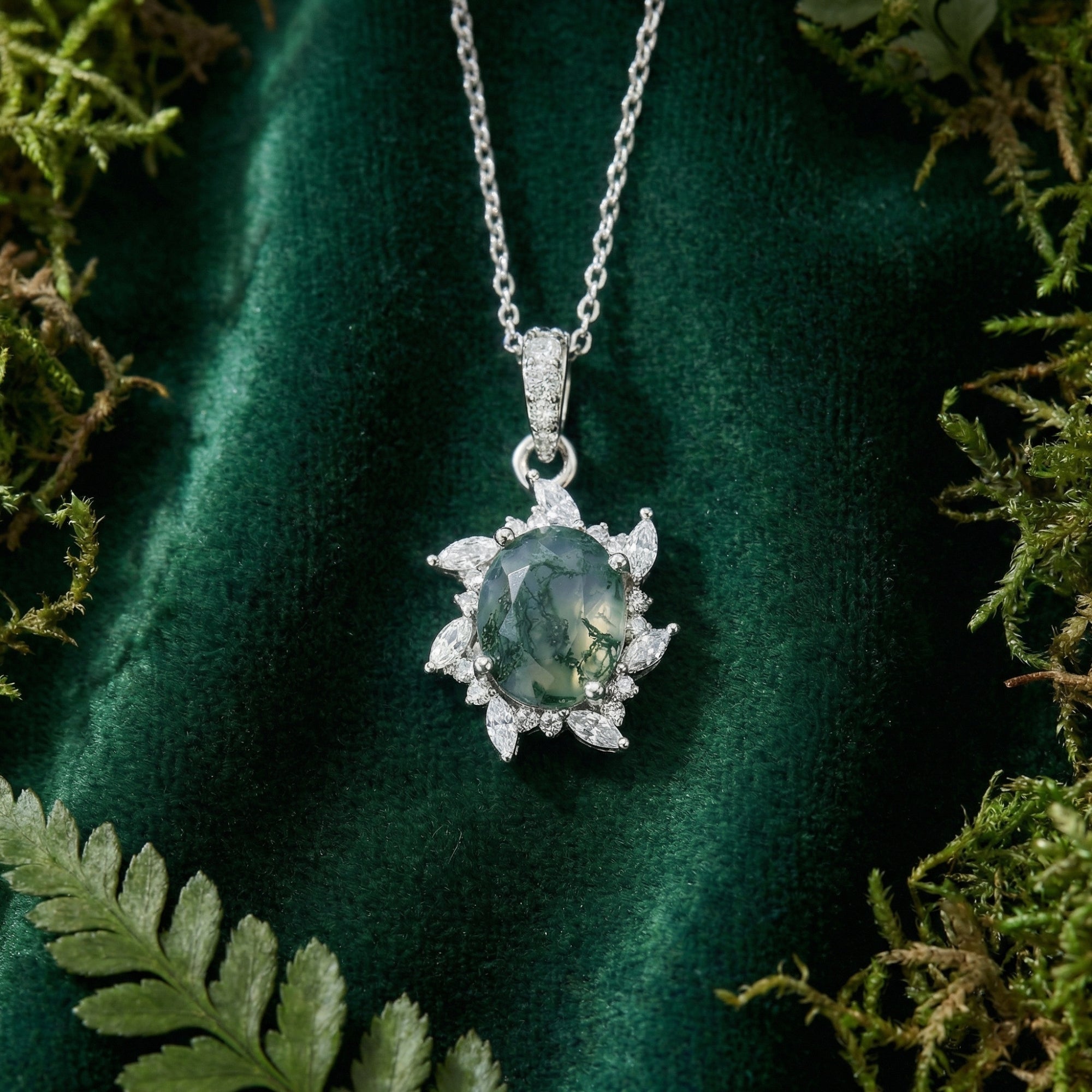 Close-up of the oval-cut moss agate stone and starburst sterling silver setting on green velvet.