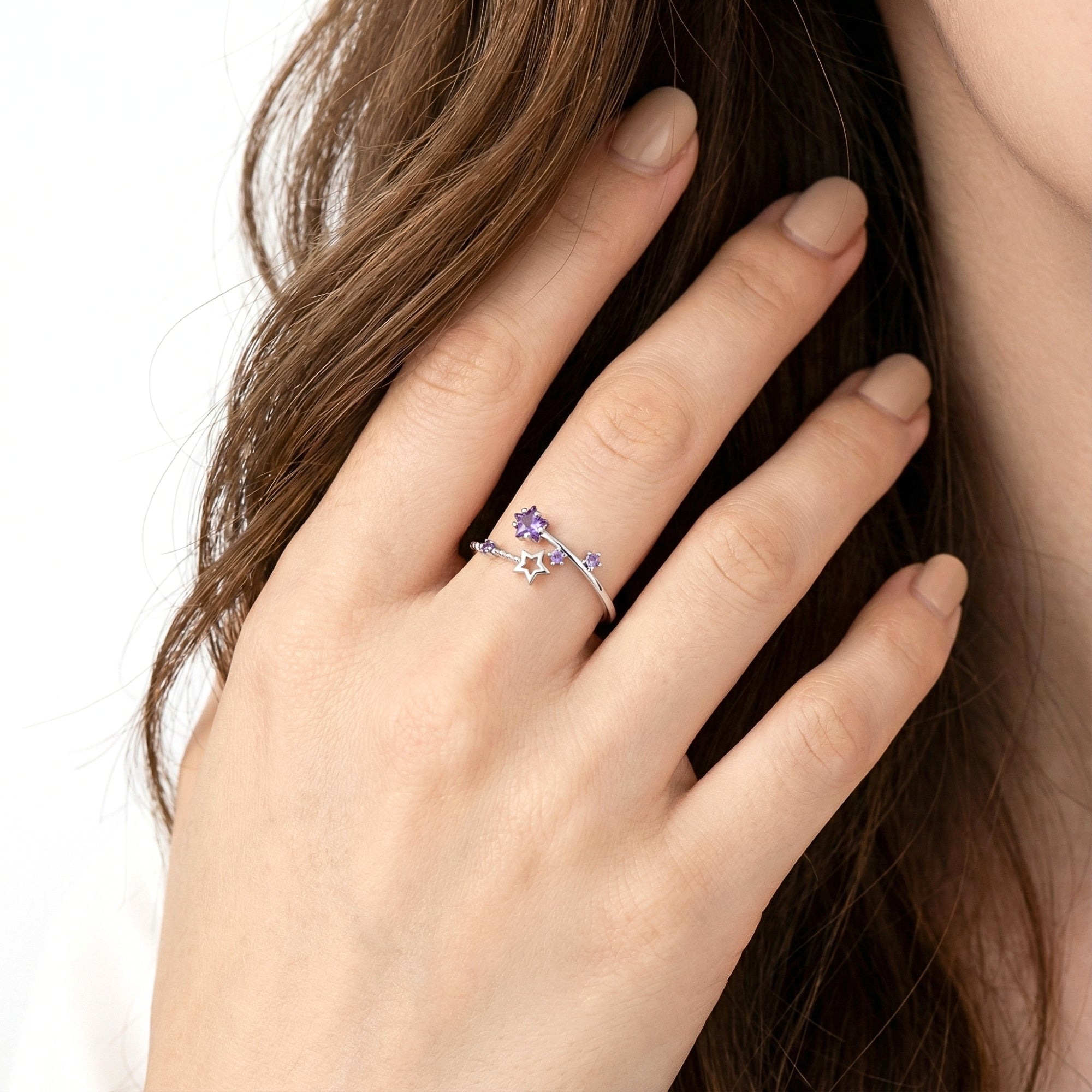 Woman's hand wearing the S925 sterling silver Galaxia ring with star-cut purple simulated amethyst.