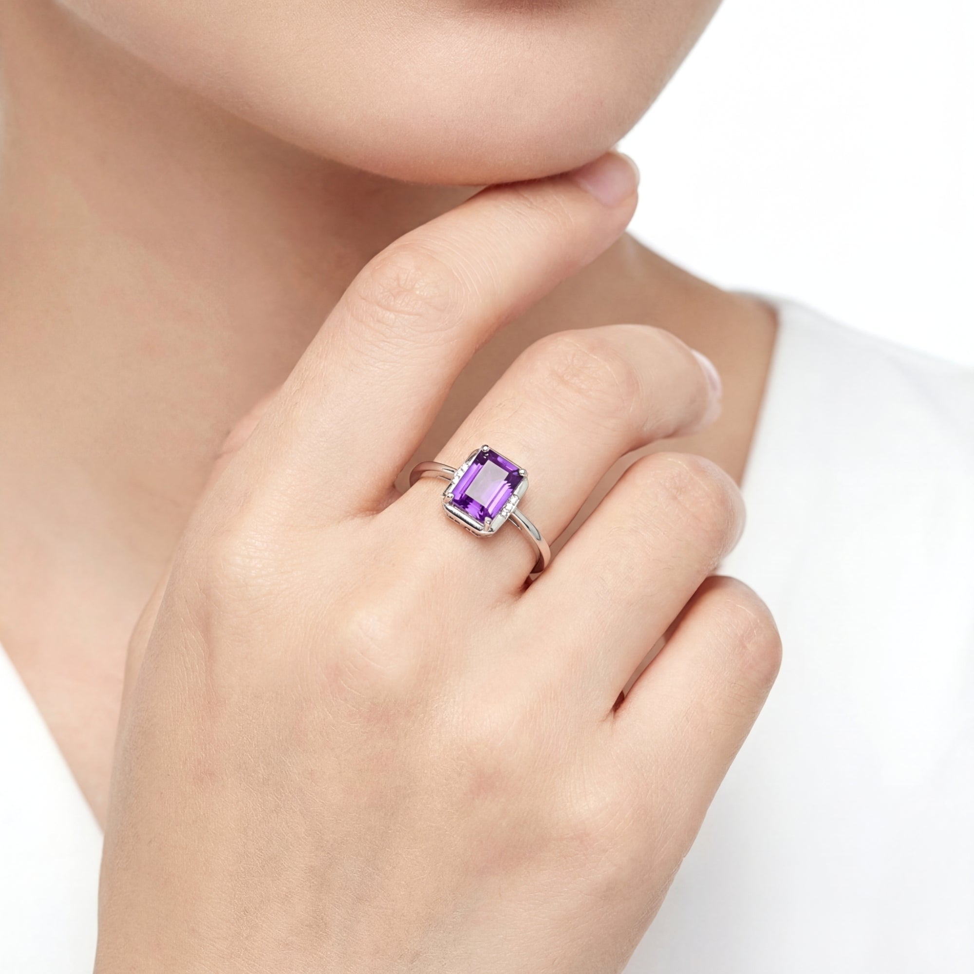 Model wearing the emerald cut simulated amethyst solitaire ring in sterling silver on her ring finger.