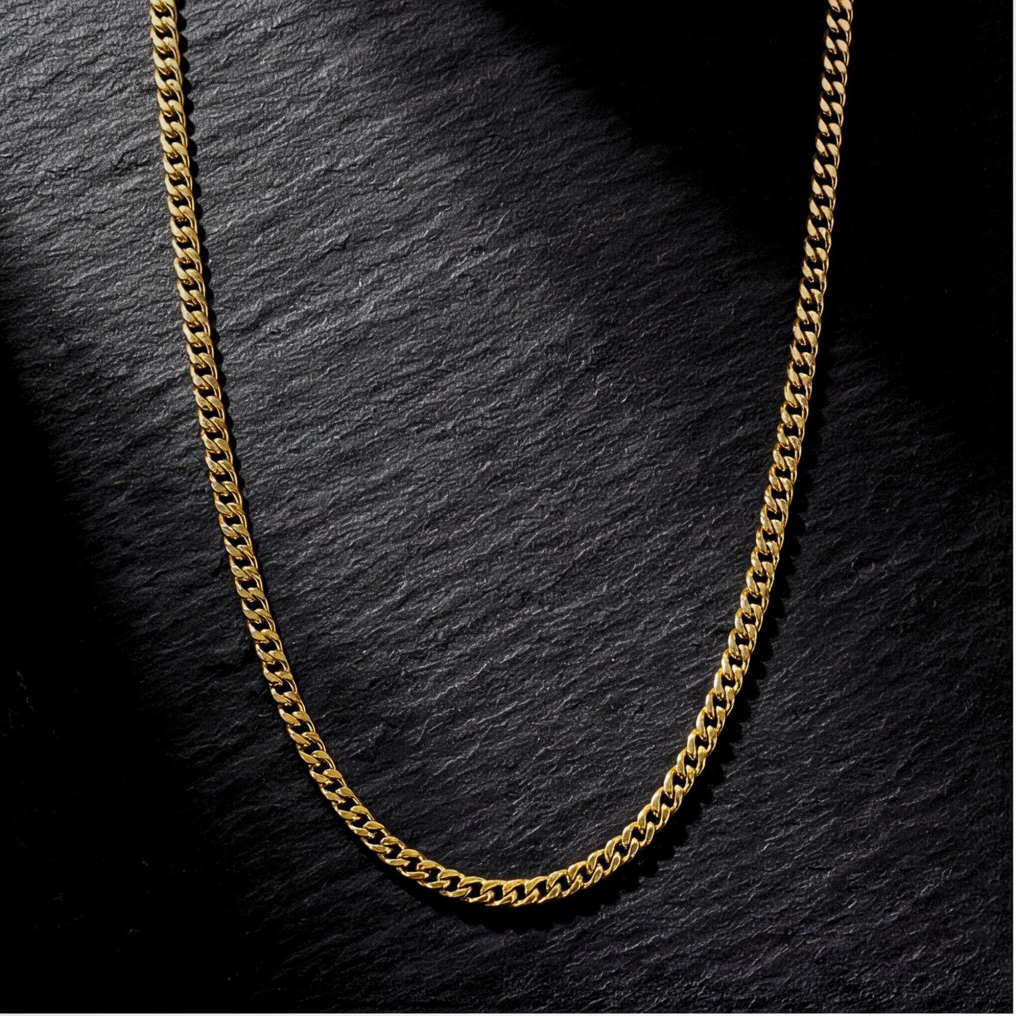 Top-down view of the 2mm gold Connell stainless steel curb chain on a dark slate background.