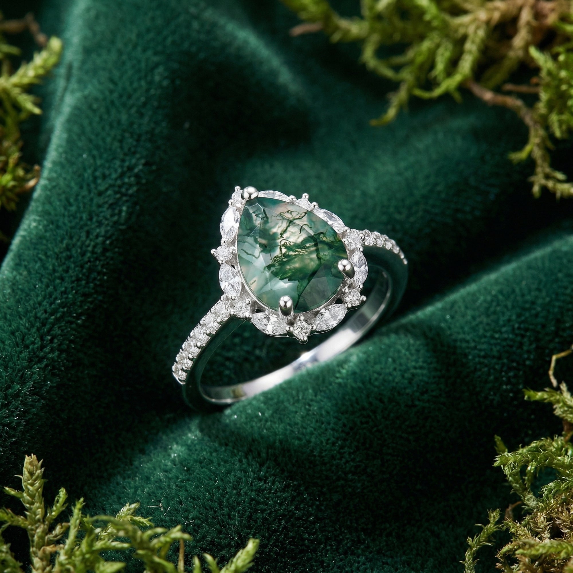 Macro view of a pear cut moss agate ring featuring a marquise diamond halo and S925 sterling silver band.