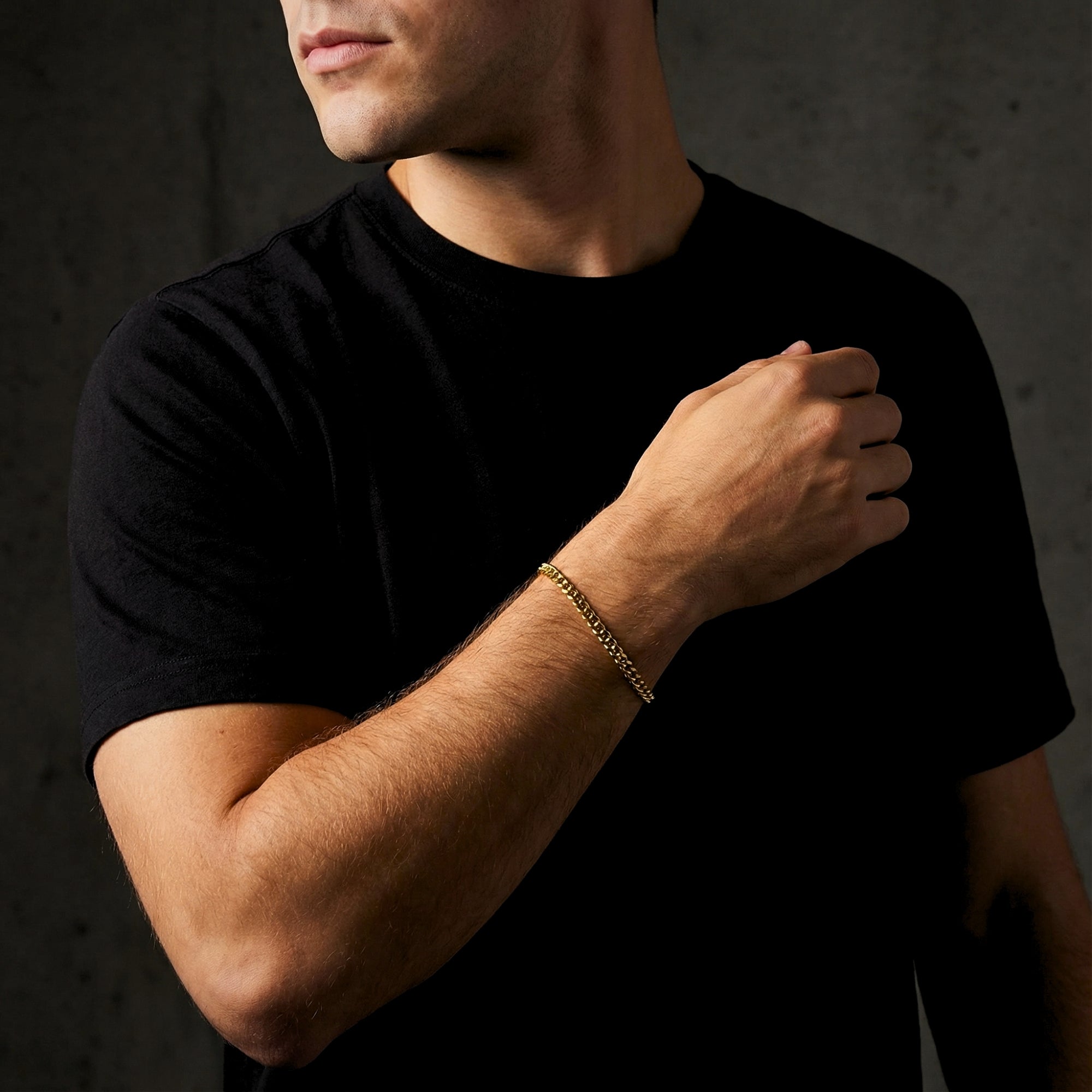 Men's gold stainless steel 5mm Cuban link bracelet worn on a wrist, paired with a black t-shirt.