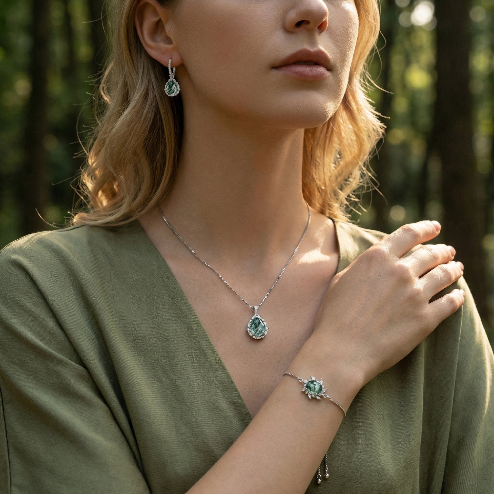 Sterling silver Moss Agate jewelry set including necklace, earrings, and bracelet worn by a model in nature.