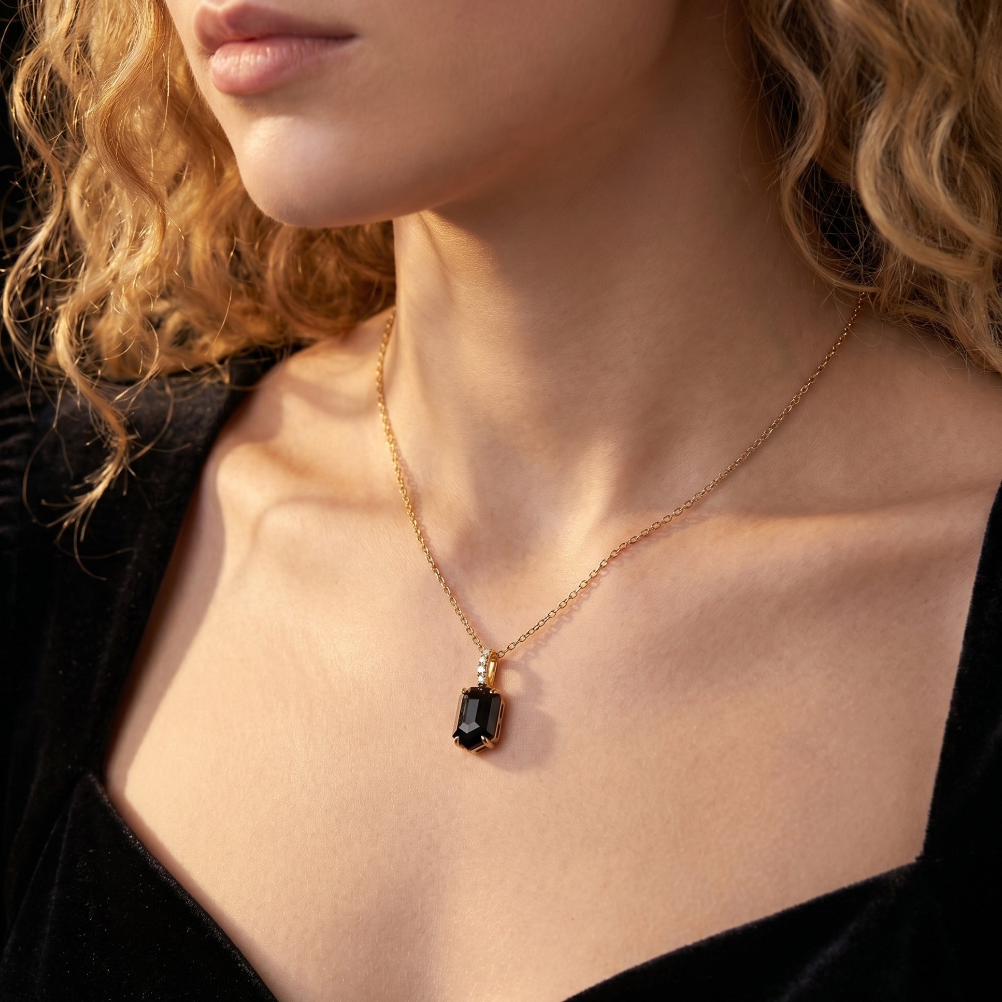 Model wearing the Noctis black onyx necklace in 18K gold plated silver against a black velvet dress.