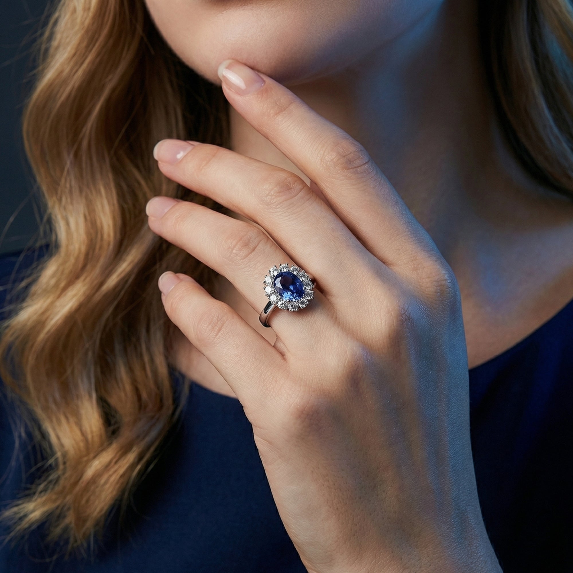 Close-up of the oval natural tanzanite halo ring in sterling silver worn by a model.