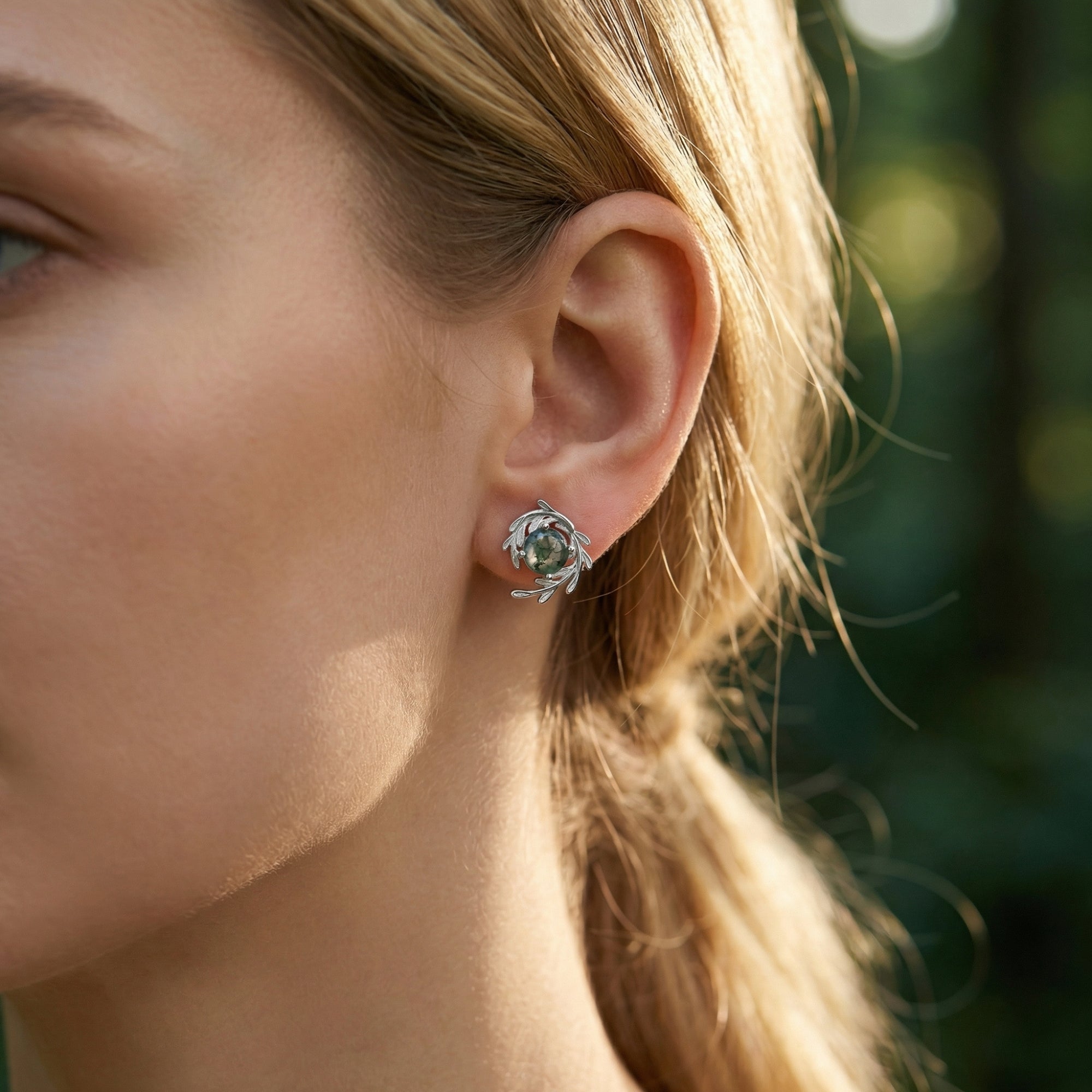 Side view of a model wearing a sterling silver vine wrap stud earring with a round moss agate stone.