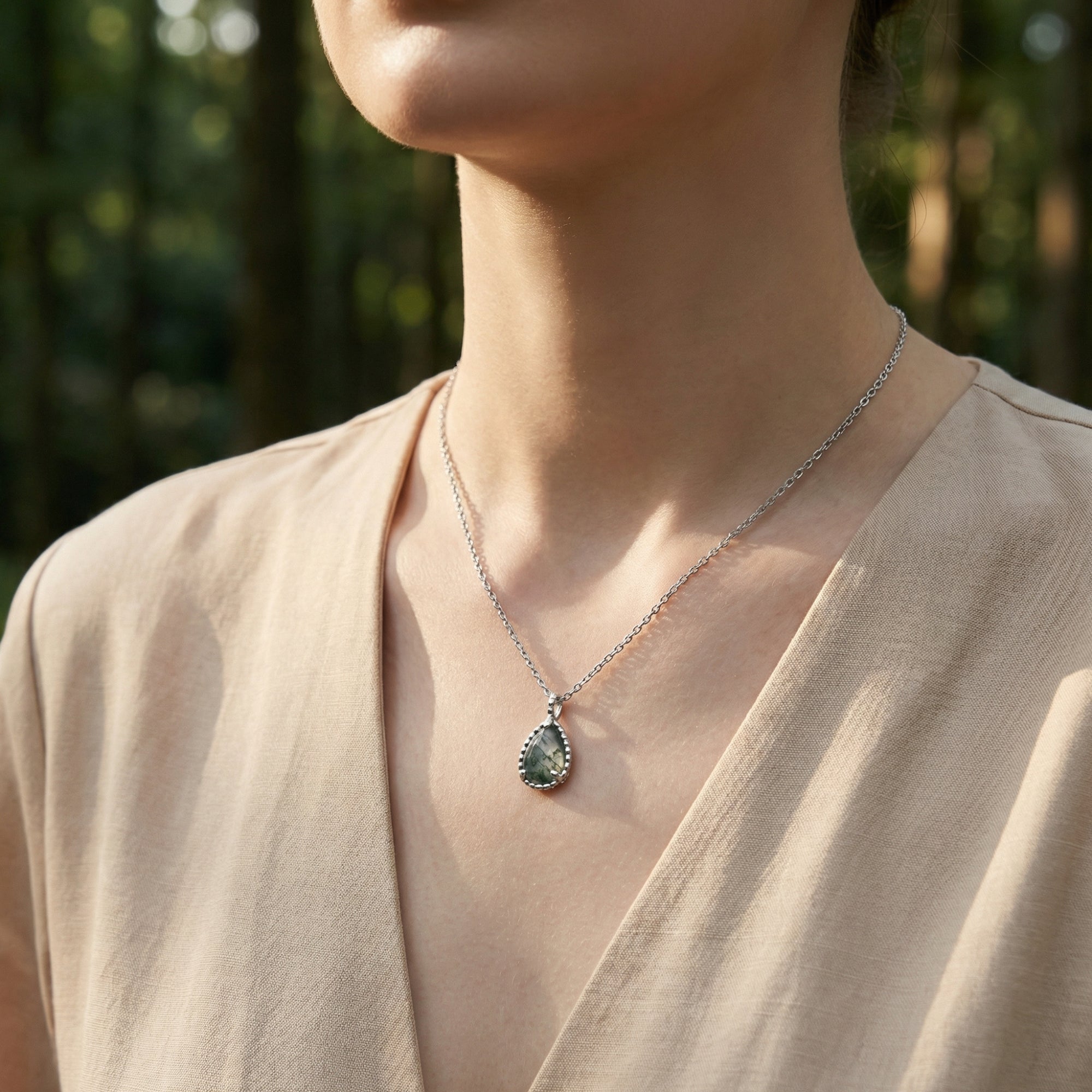 Sterling silver teardrop moss agate basket weave necklace worn by a model in a natural forest setting.