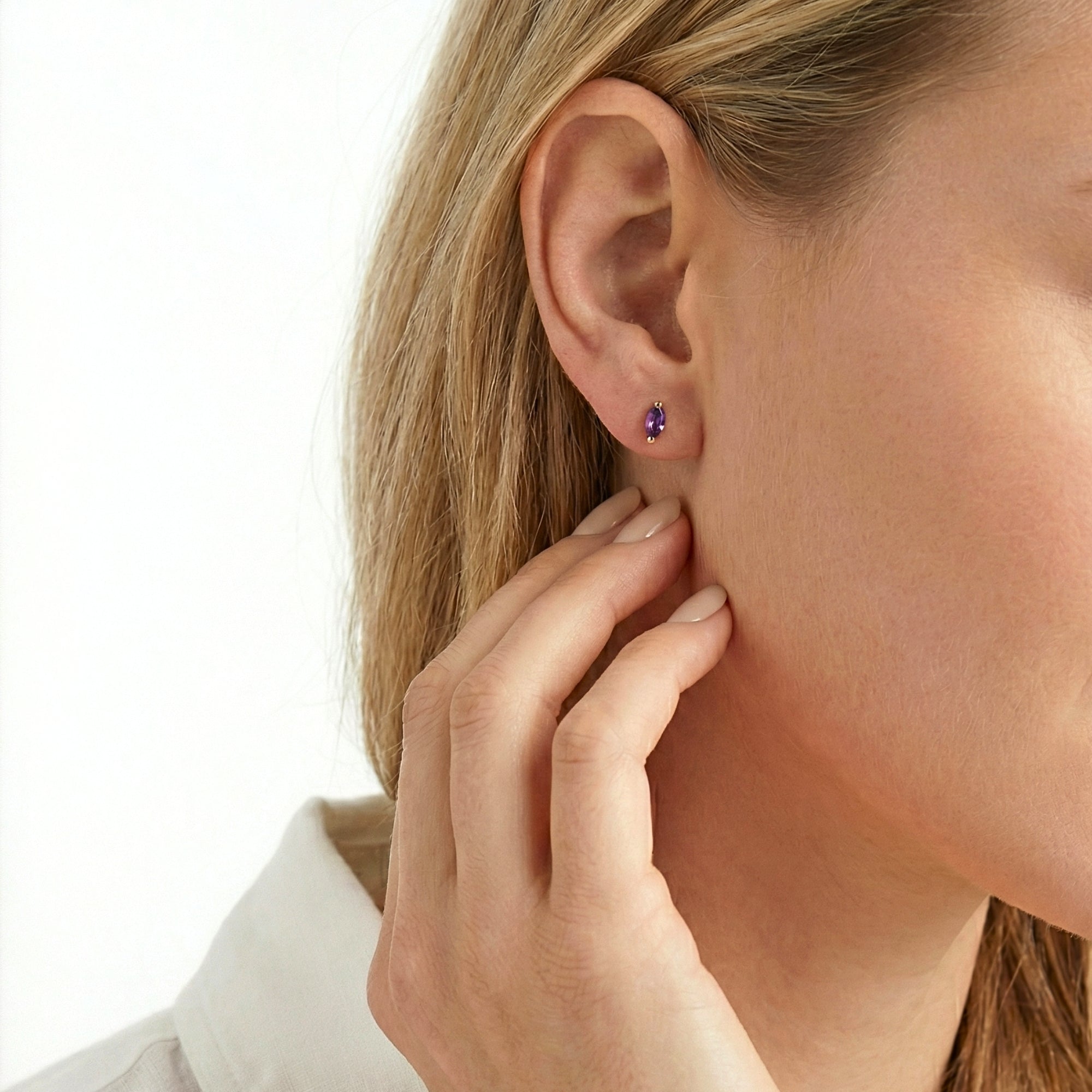 Close-up of The Marcella Studs marquise-cut purple simulated amethyst earring in 18K gold vermeil on a model's ear.