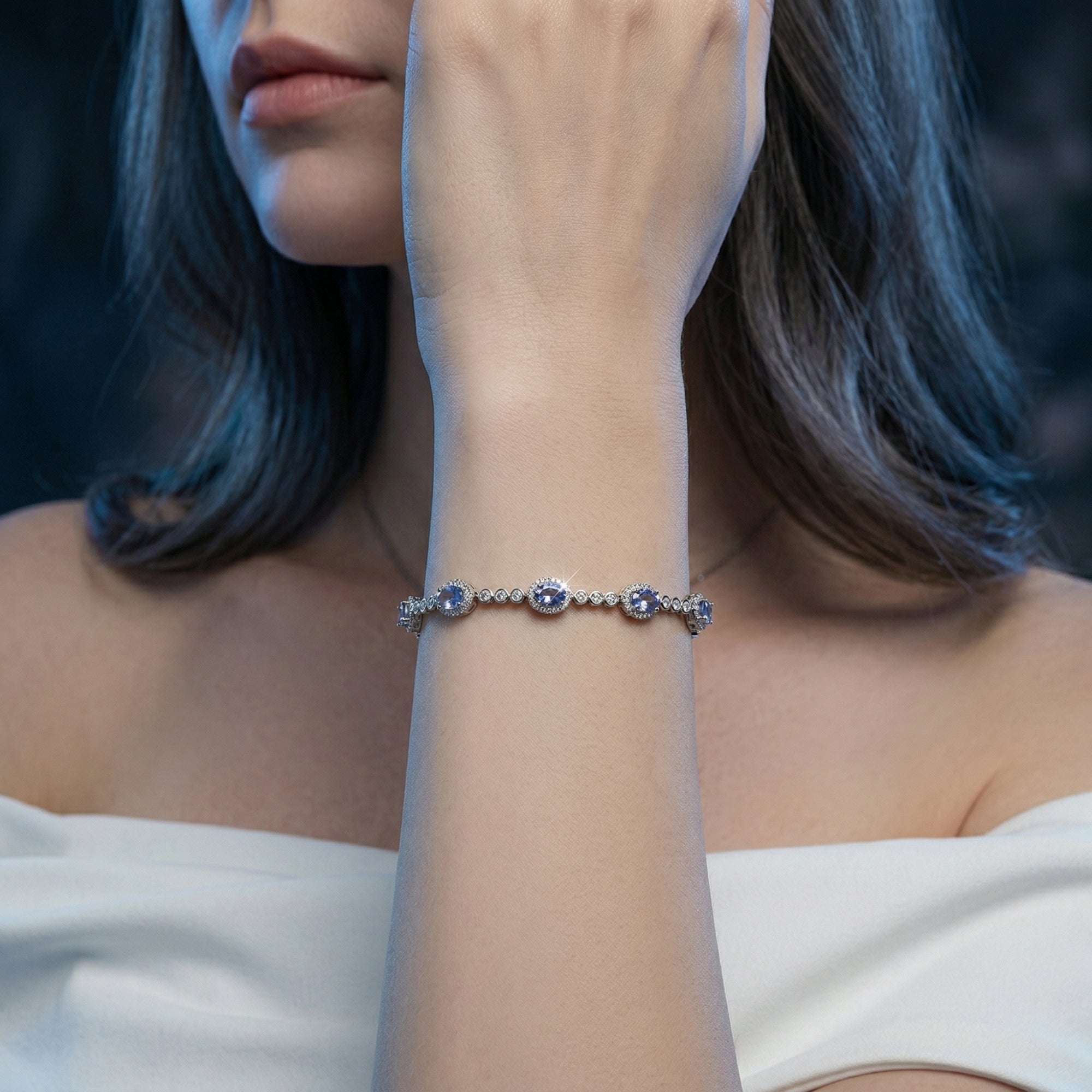 The Xanthe sterling silver line bracelet with eight oval cut natural tanzanite stones worn on a woman's wrist.