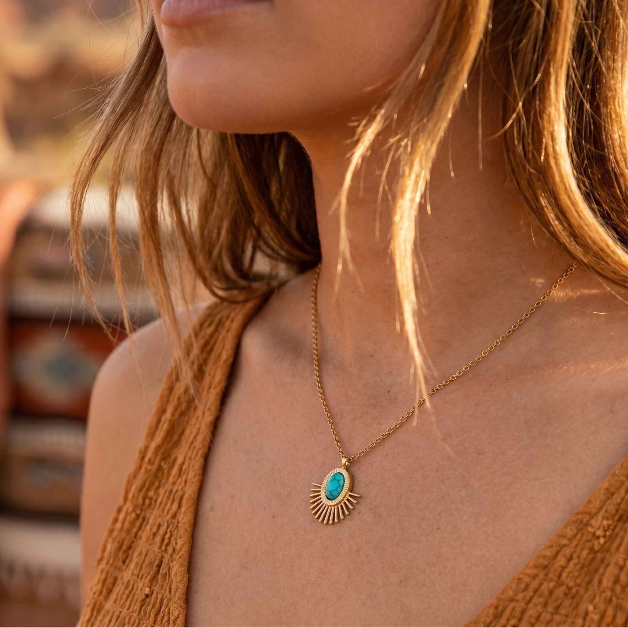 Southwestern gold sunburst turquoise necklace worn by a model with a blurred desert landscape background.