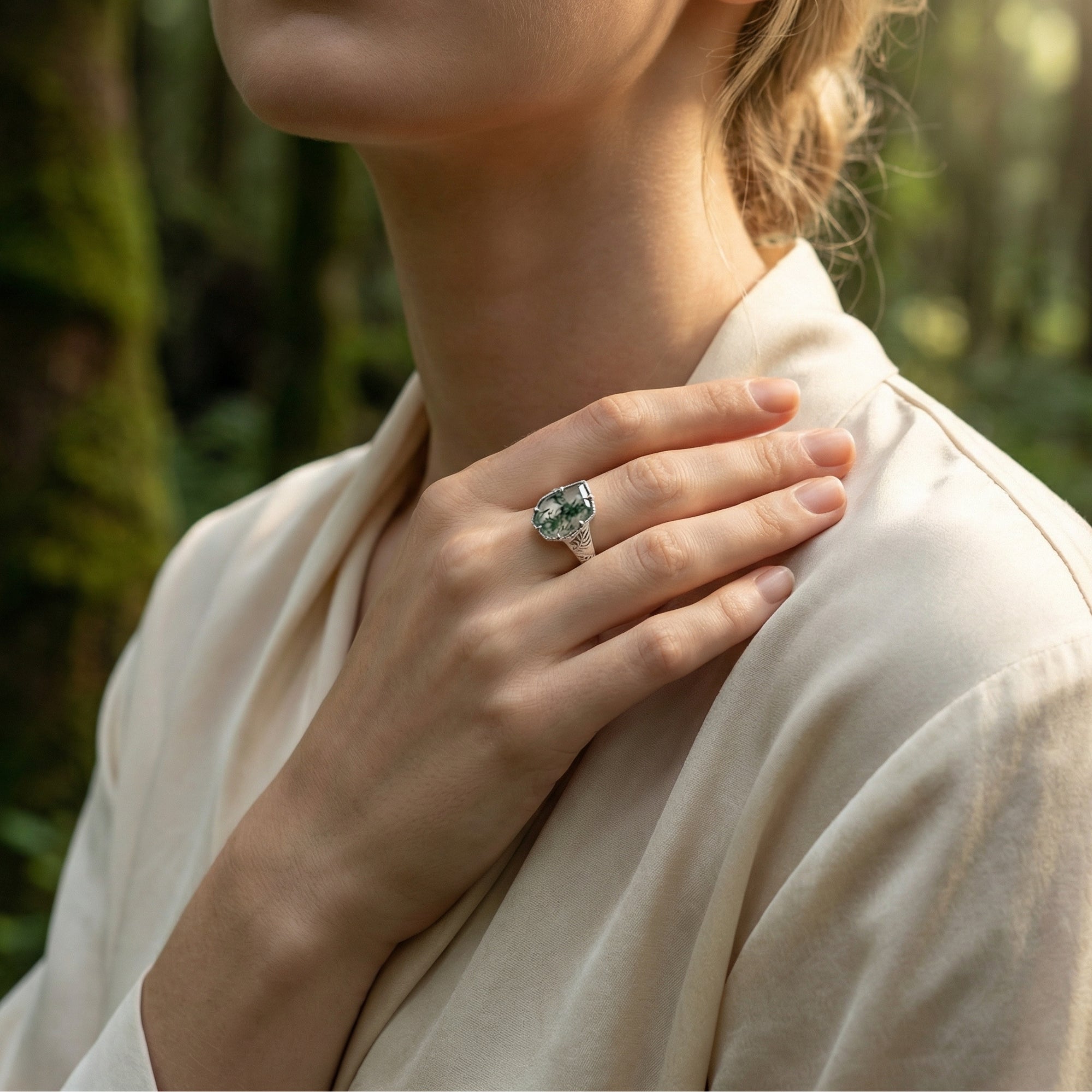 Sterling silver moss agate ring with leaf design worn by a model in a forest lifestyle setting.