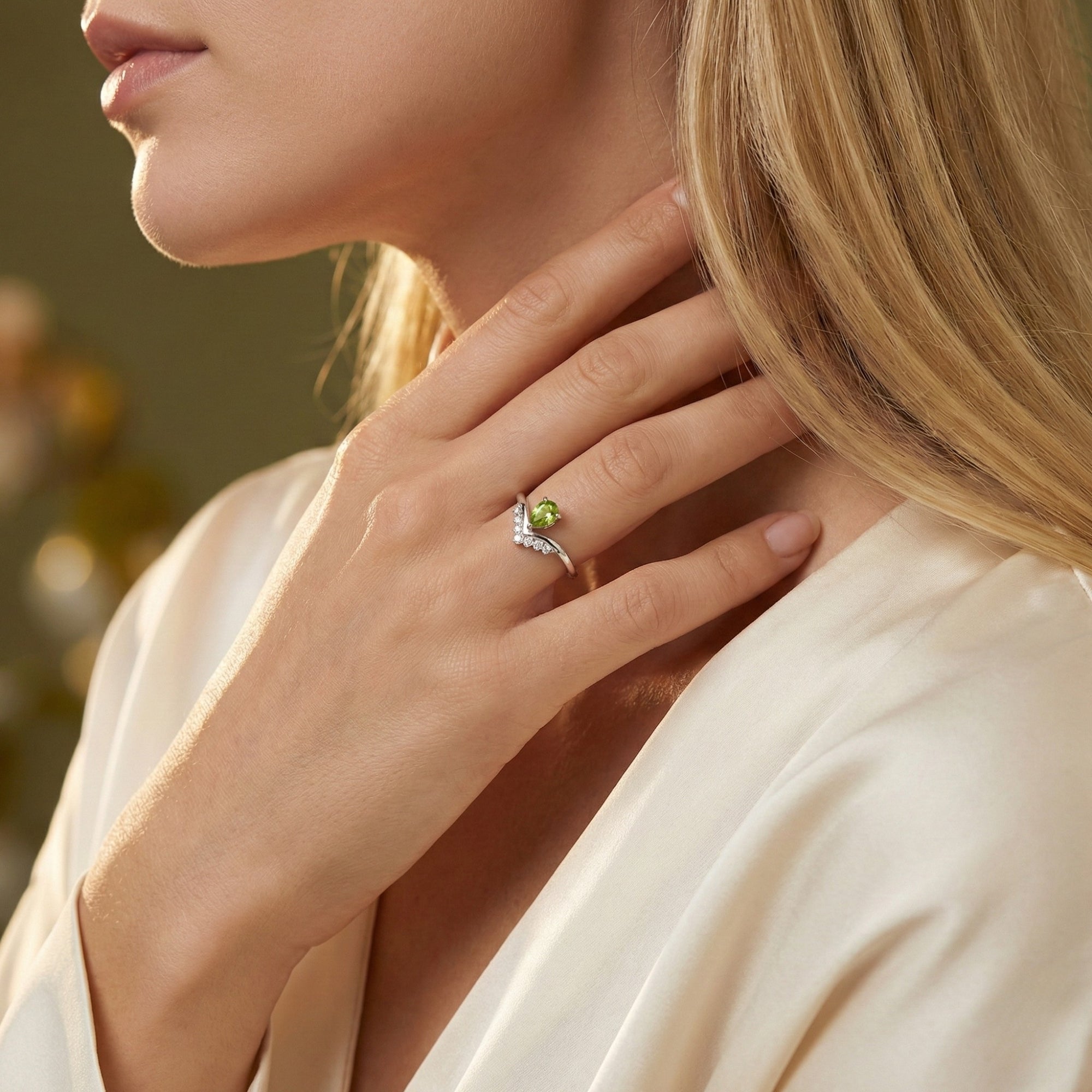 A woman wearing the natural pear cut peridot sterling silver ring, highlighting its vibrant green color.