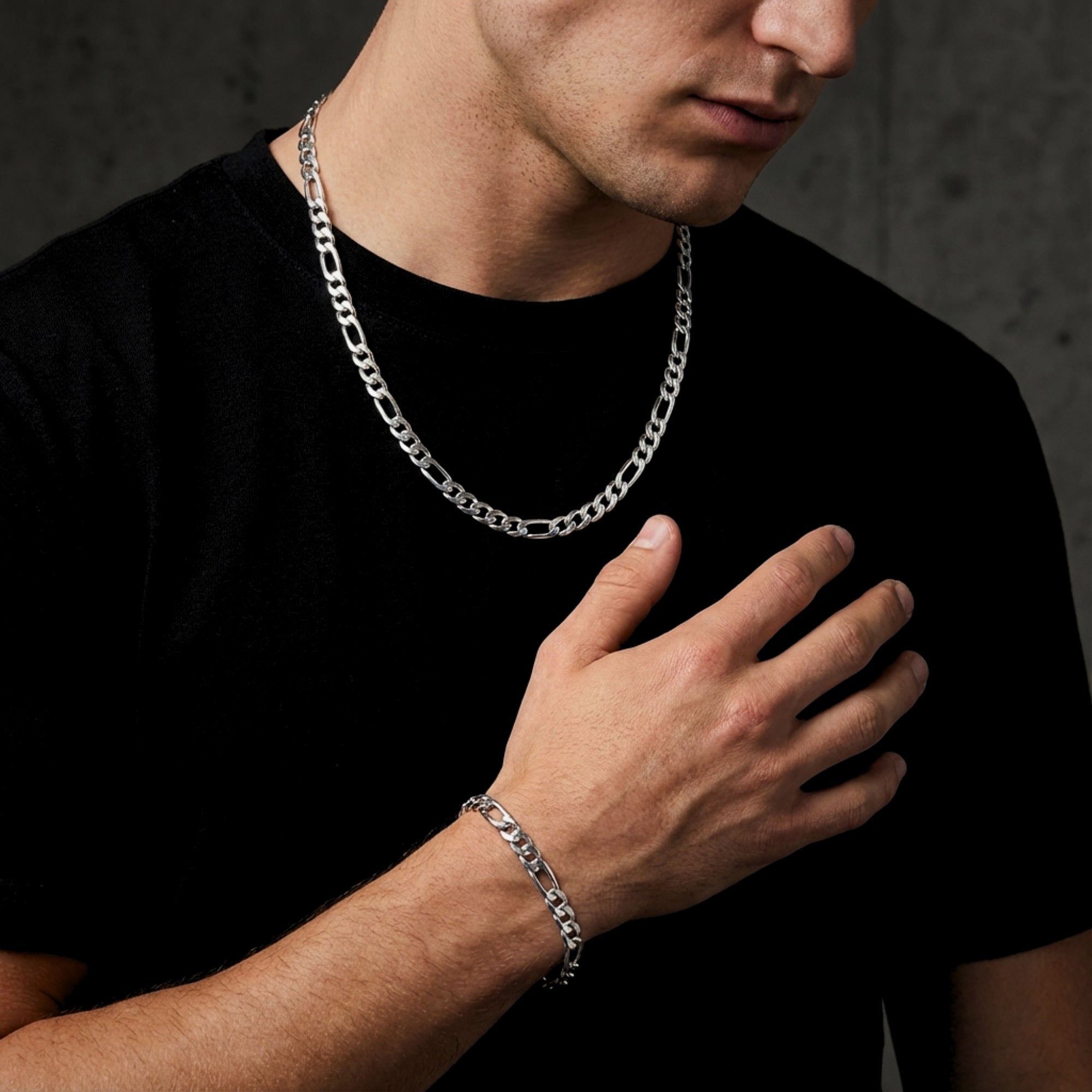 Polished silver 8mm Figaro chain and bracelet set worn by a man in a black t-shirt.