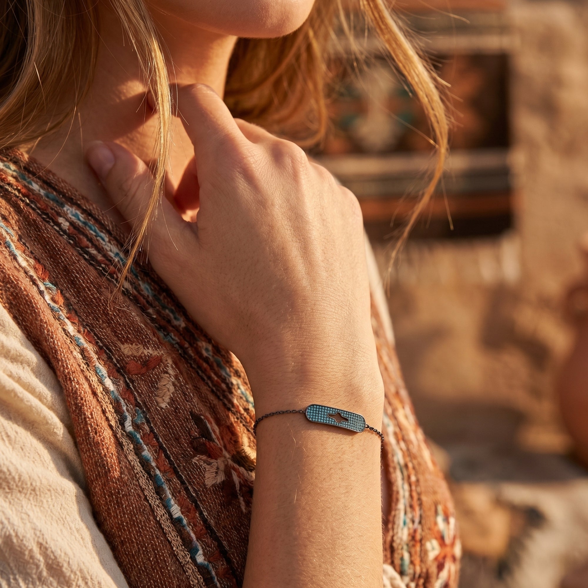Southwestern style Estrella turquoise bracelet in oxidized silver worn on a woman's wrist in a desert setting.