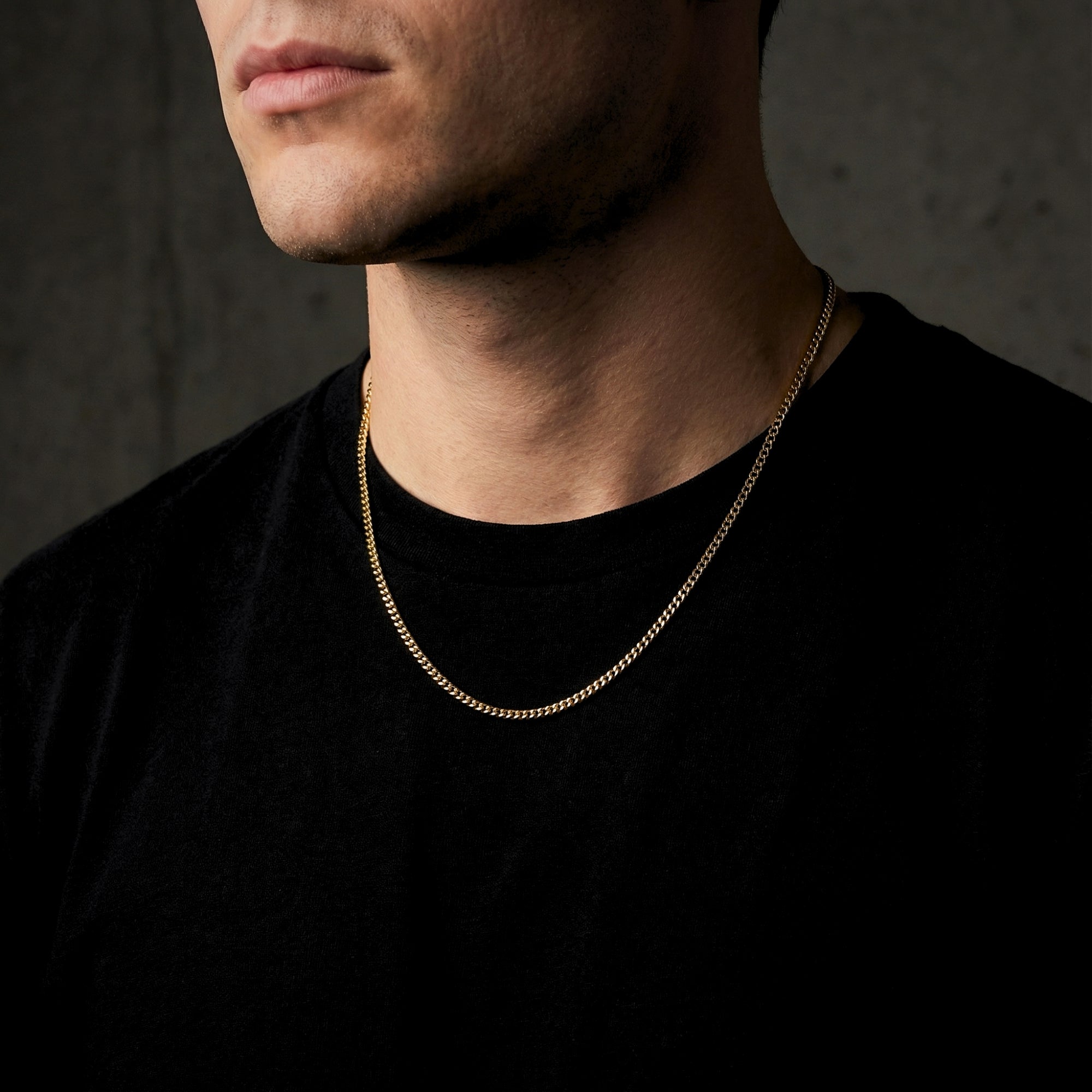 Men's 2mm gold Connell stainless steel curb chain necklace worn by a model in a black shirt.