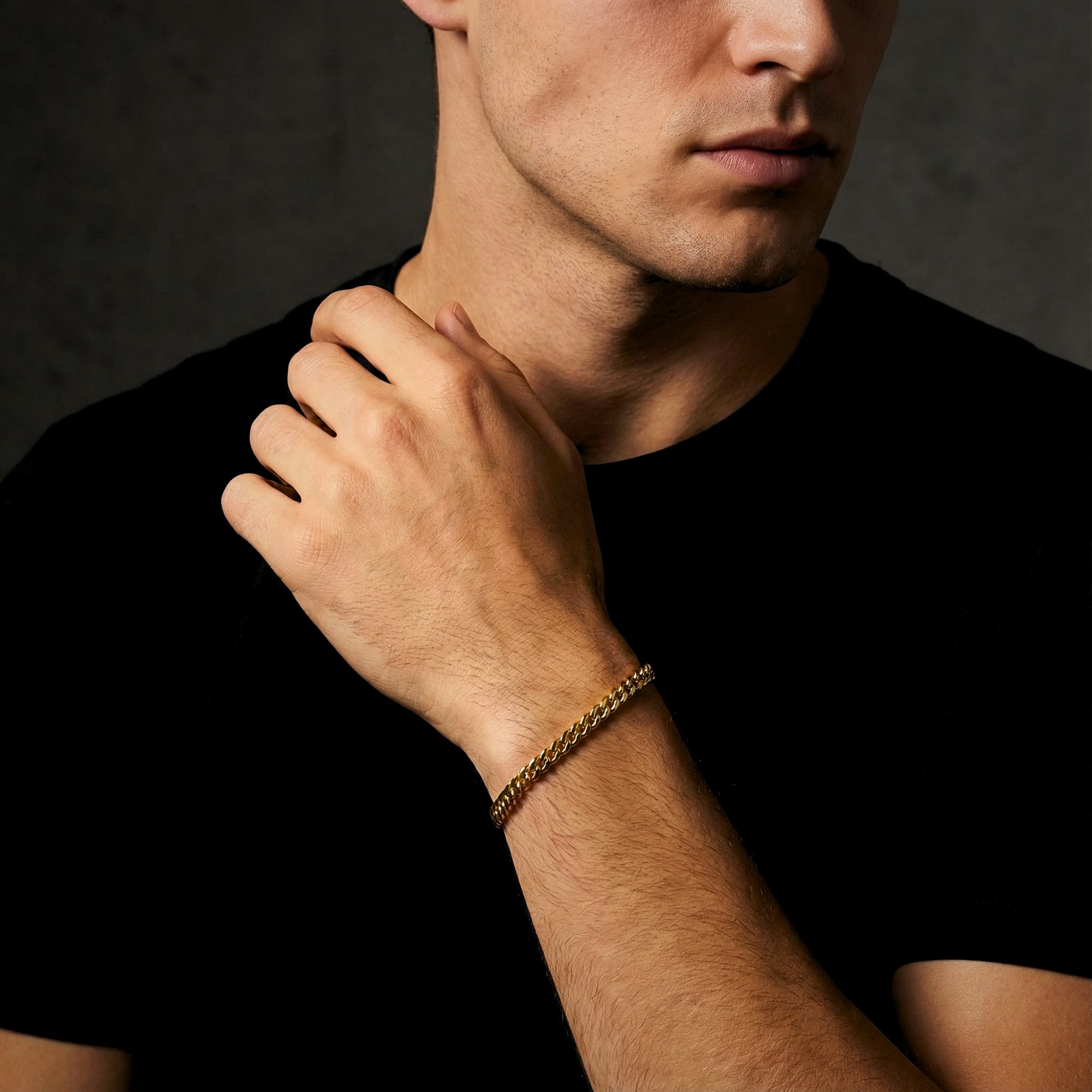 Close-up of the 5mm gold stainless steel Cuban link bracelet worn on a man's wrist.