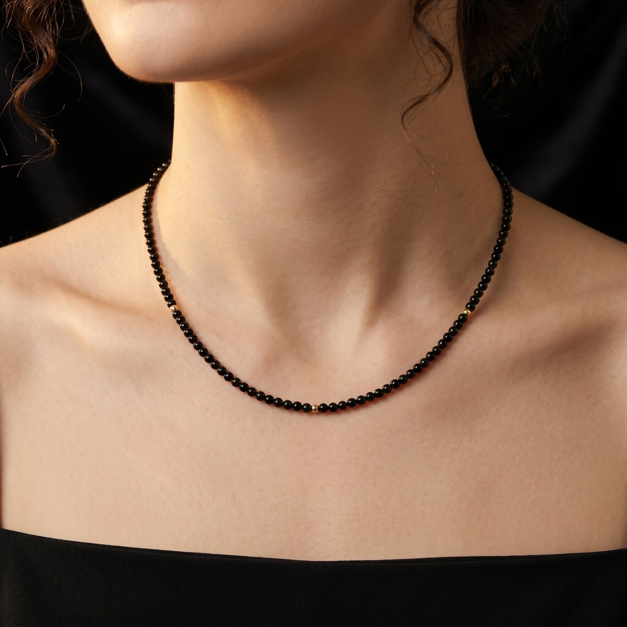 3mm polished black onyx bead necklace with 18K gold accents worn by a model, showcasing its minimalist and elegant fit.