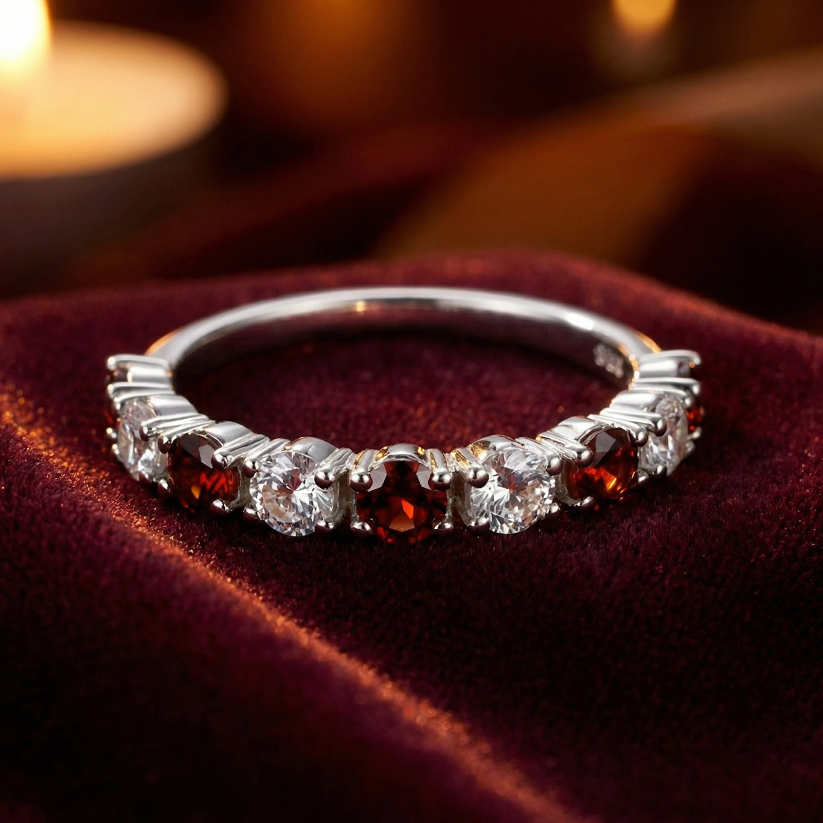 Aeliana eternity ring in S925 sterling silver with round cut simulated garnets and clear stones on red velvet.