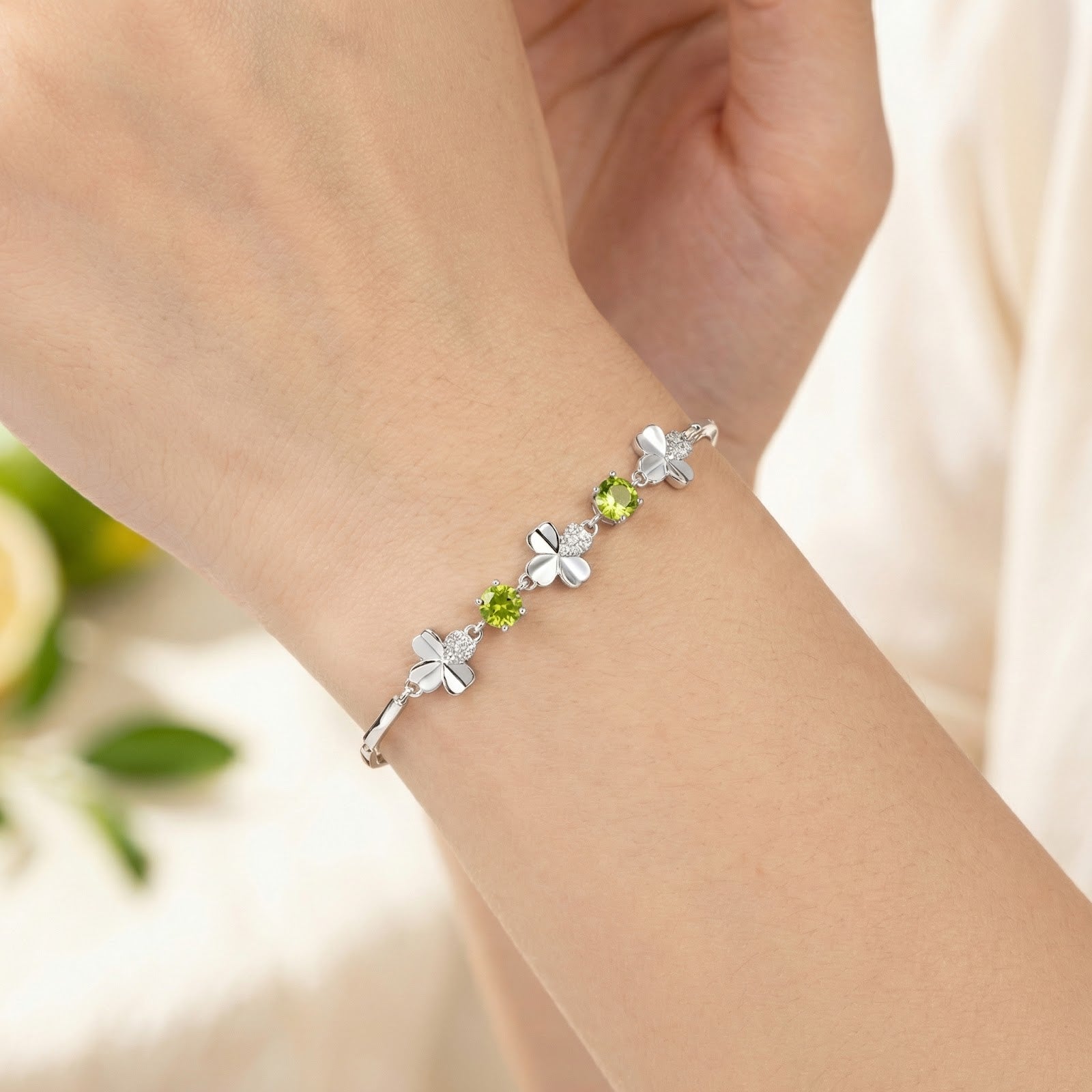 Close-up of the sterling silver clover bracelet with round peridot stones on a wrist to show size and fit.