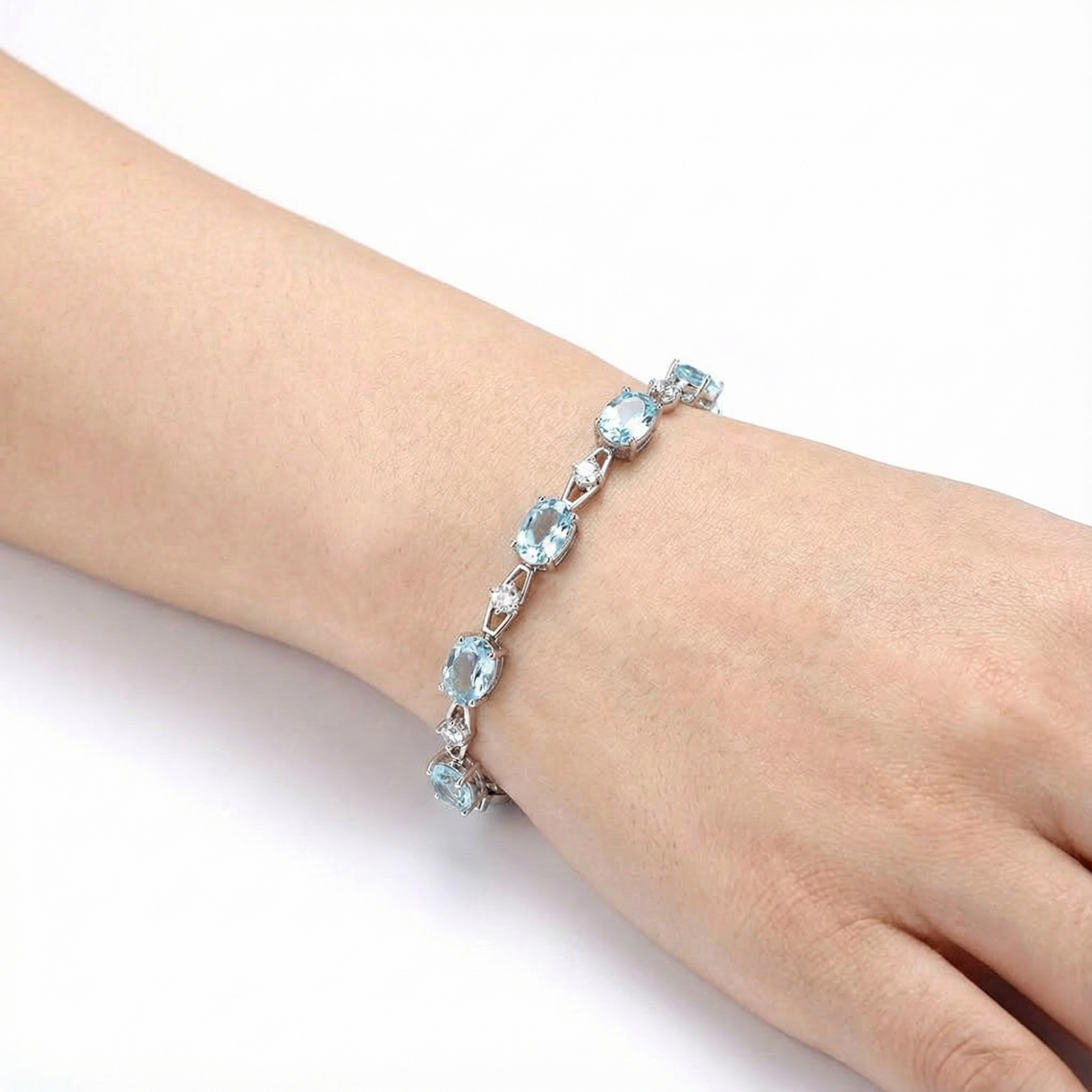 Oval cut simulated aquamarine sterling silver bracelet shown on a wrist for scale reference.