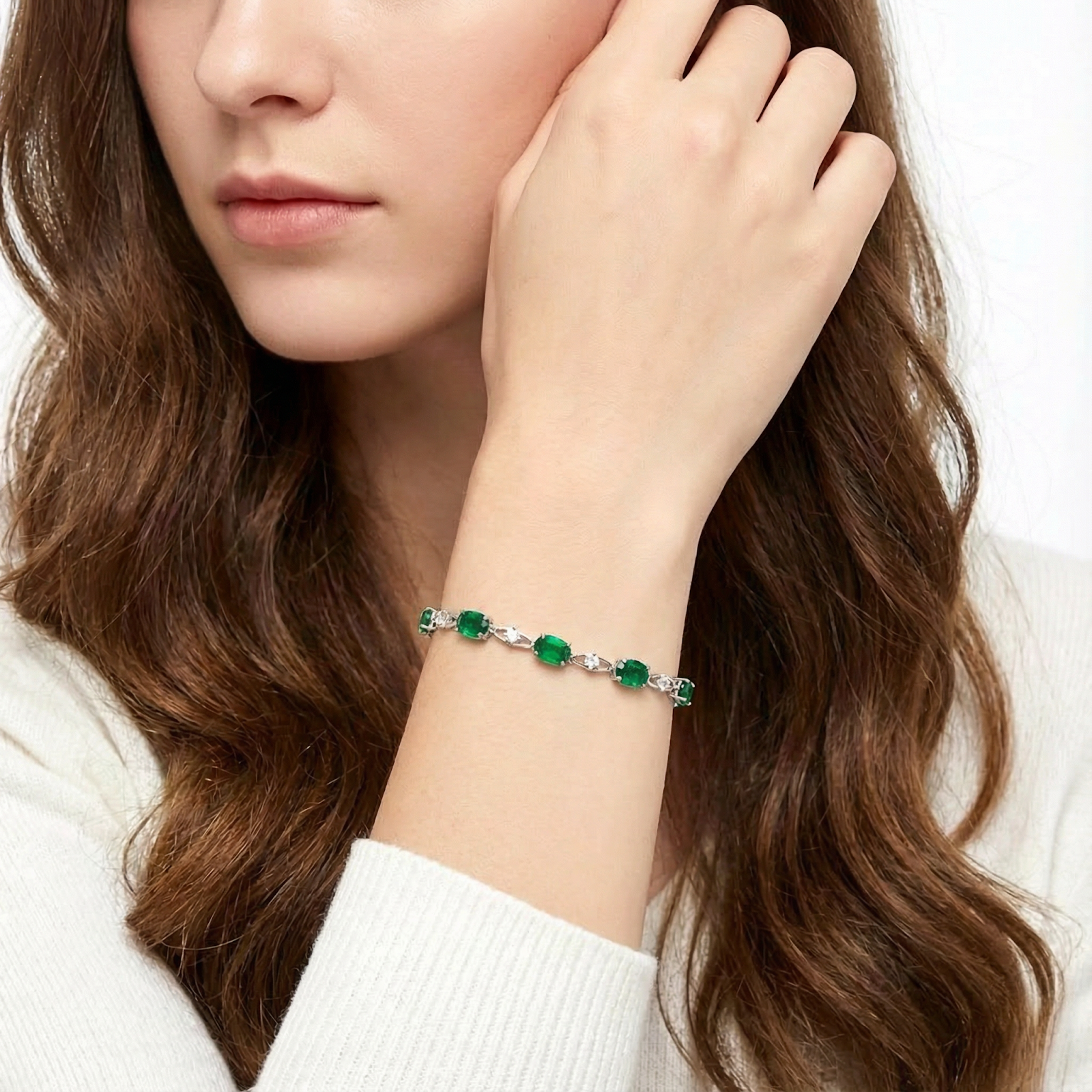 Sterling silver station bracelet with green simulated emeralds worn on a woman's wrist.