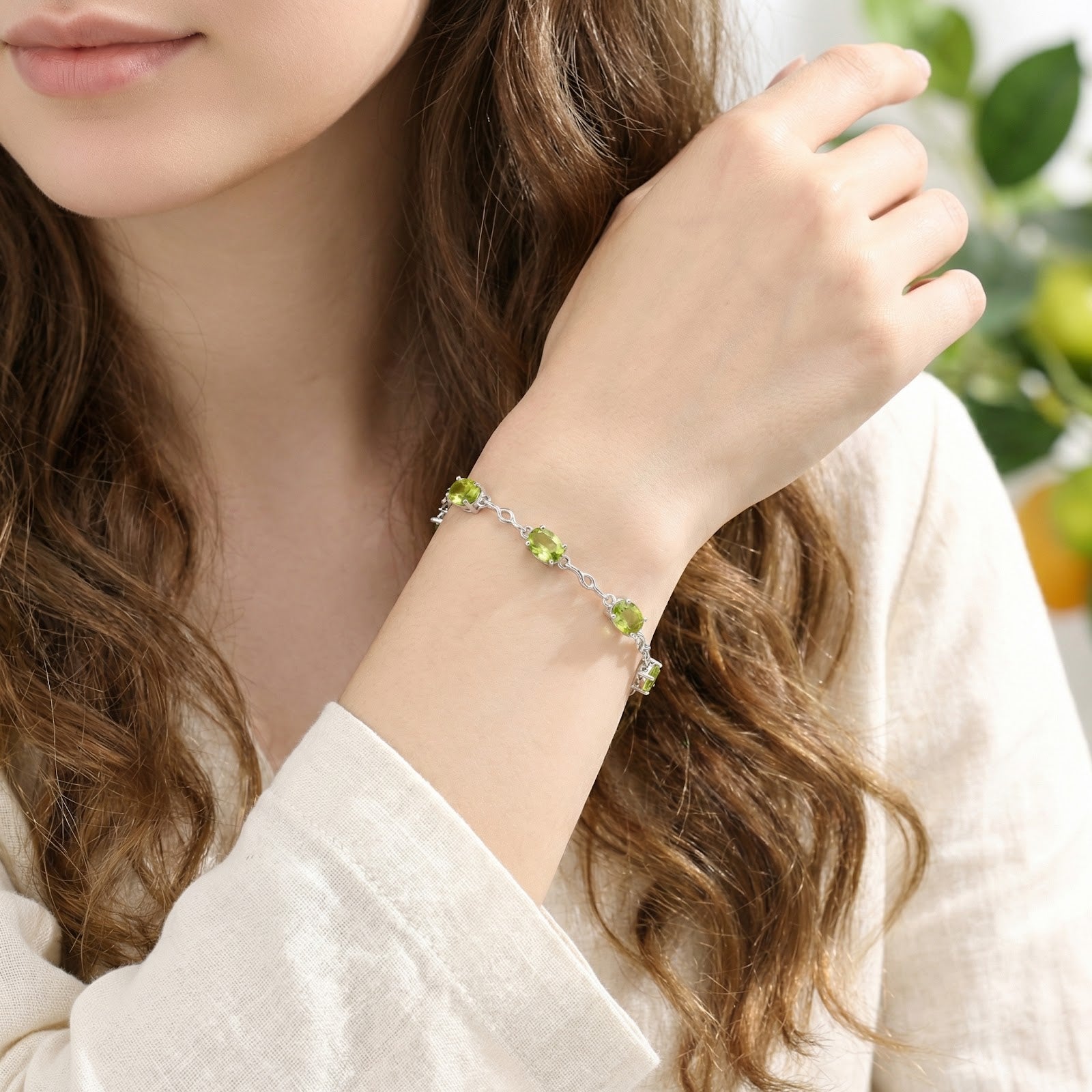 Adjustable sterling silver station bracelet with oval simulated peridot stones shown on a model.