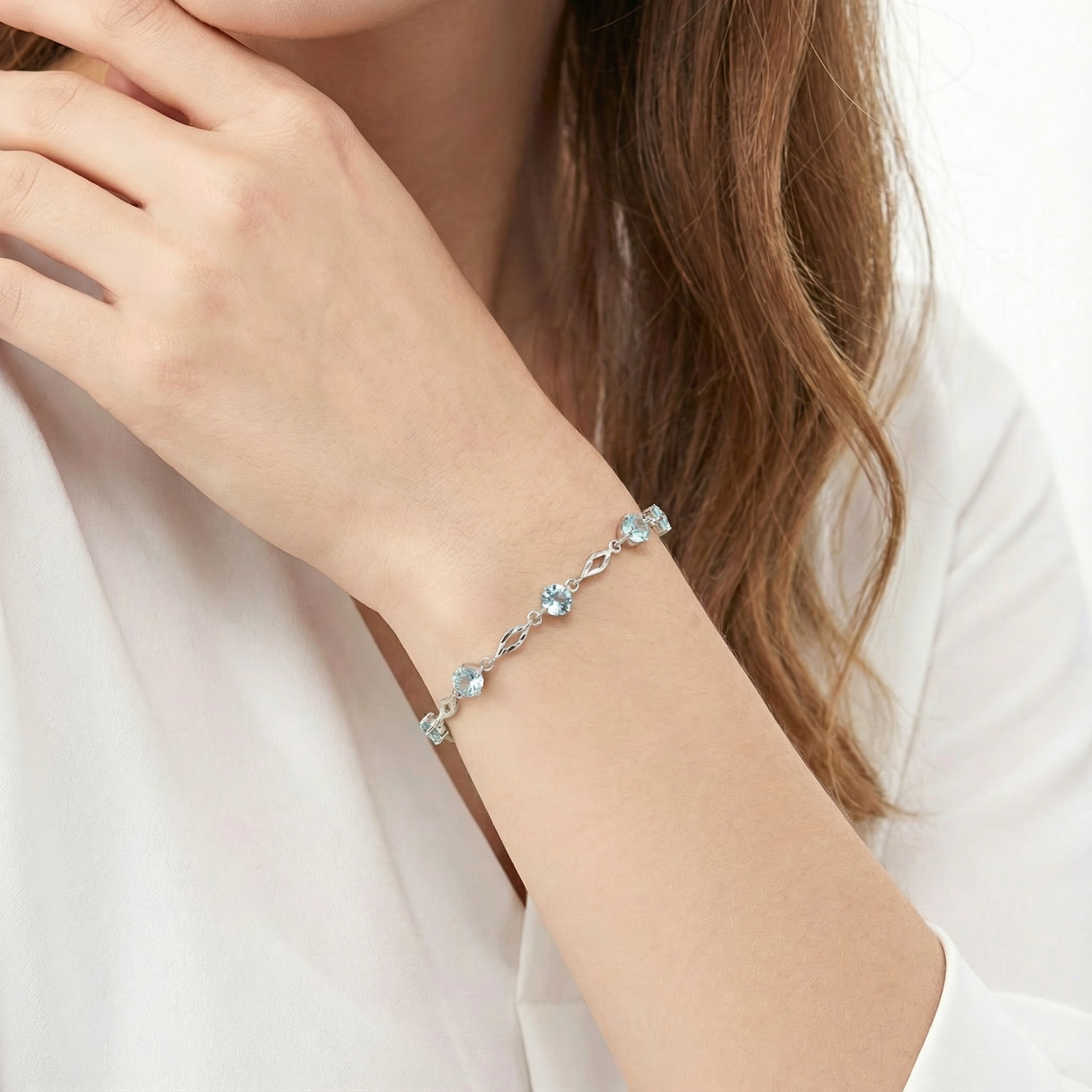 Close-up of the S925 sterling silver Etherea station bracelet with simulated aquamarine on a woman's wrist.