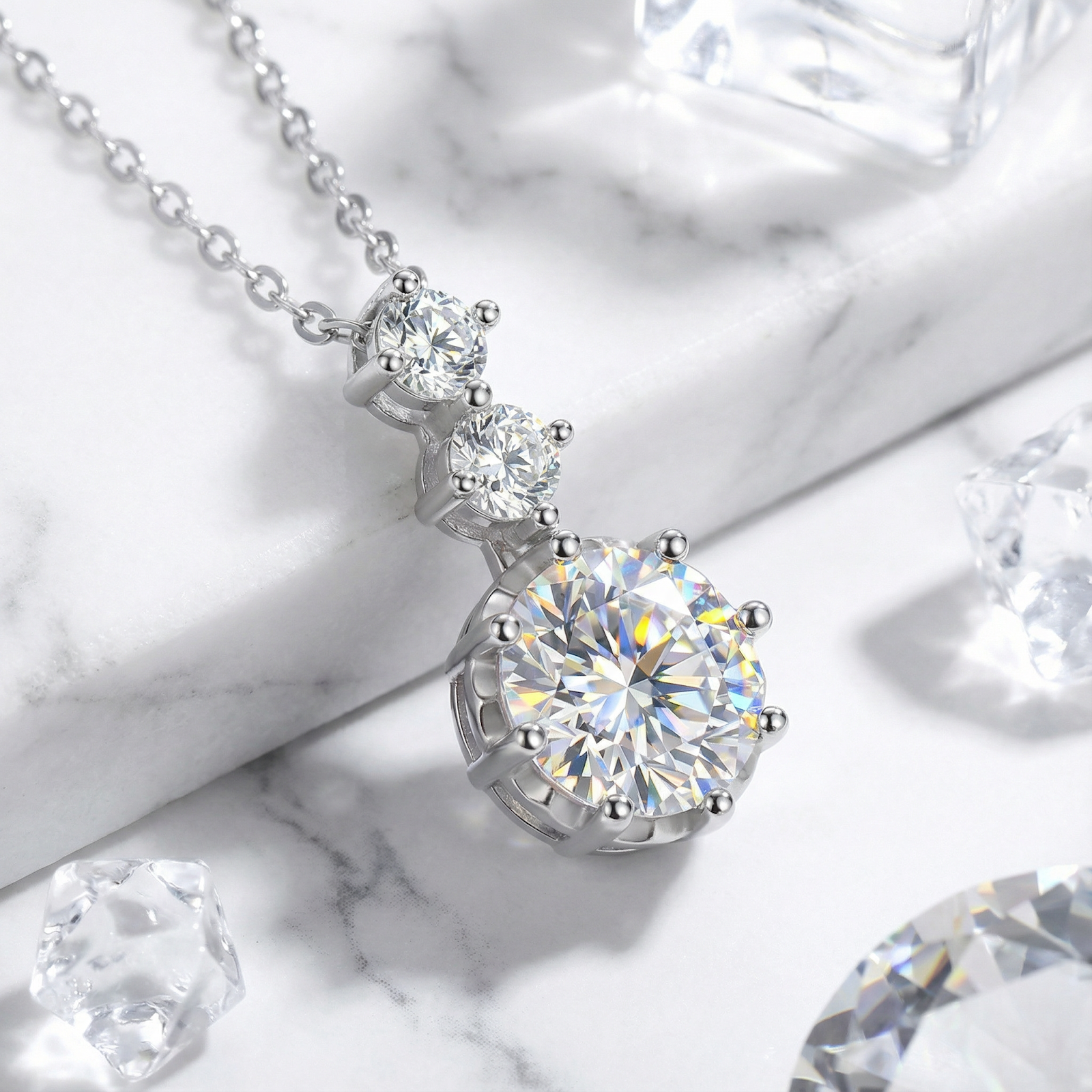 Macro view of the Aurelle Drop sterling silver necklace with three round brilliant simulated diamonds on marble.