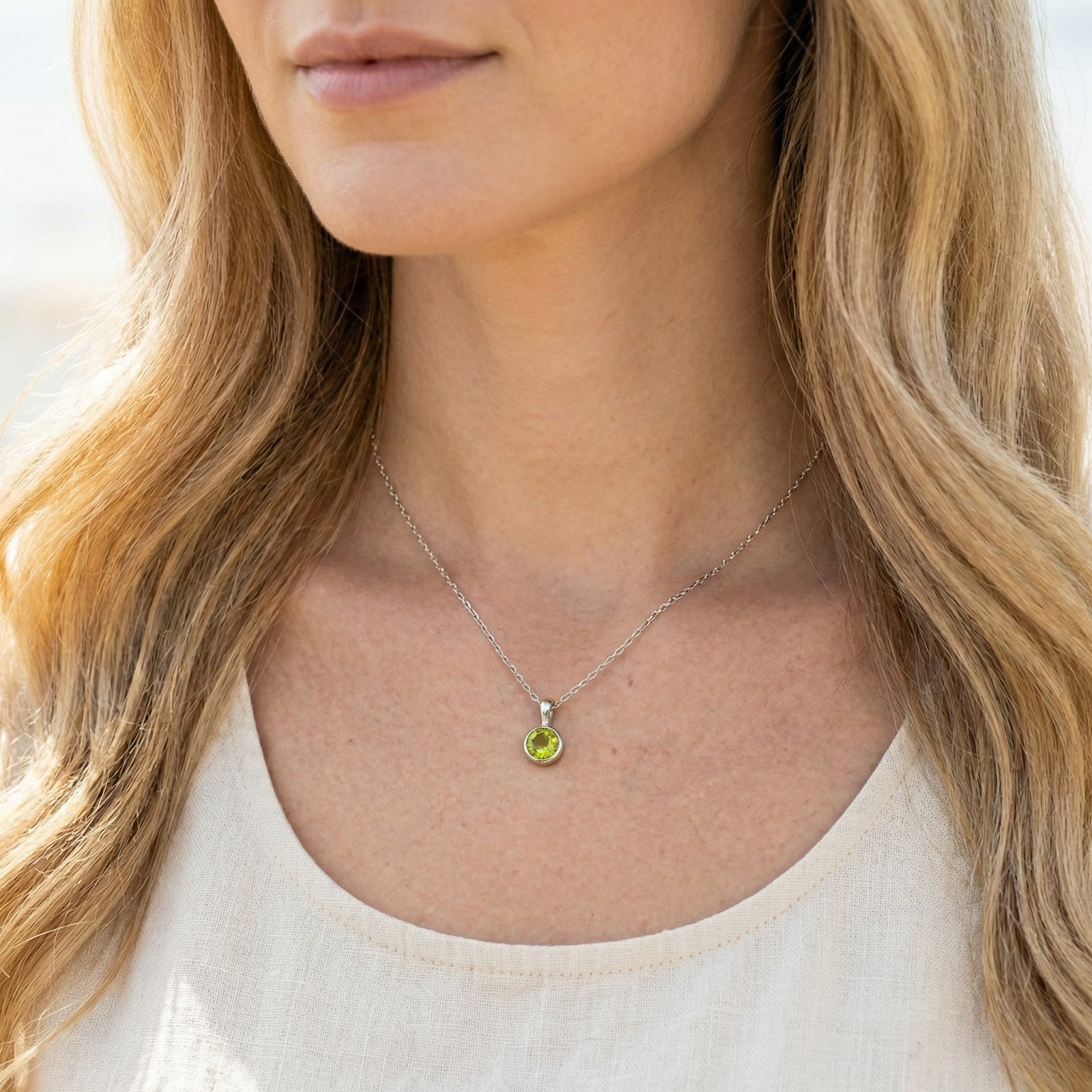 Close-up of the round-cut simulated peridot S925 sterling silver necklace worn by a woman.