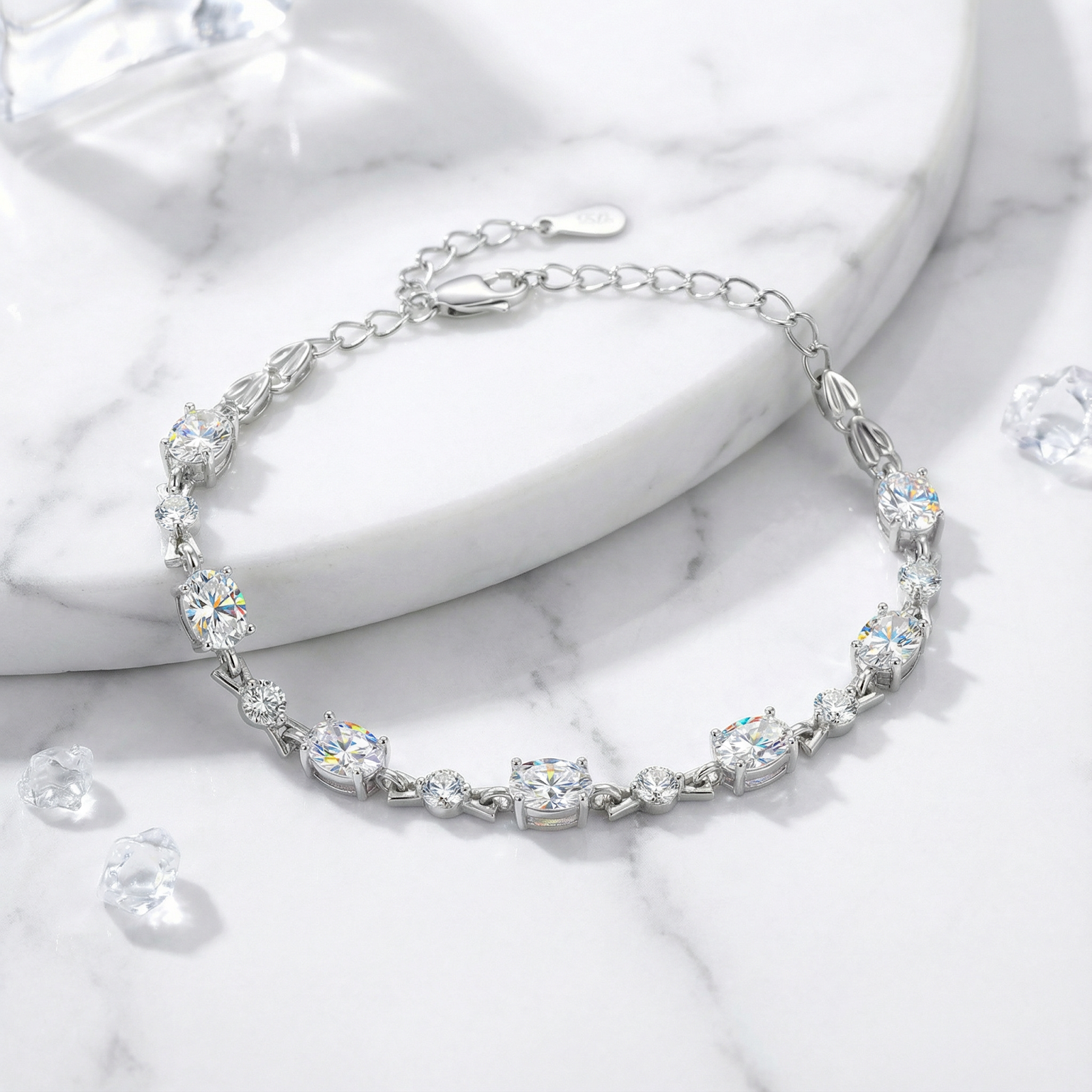 Oval cut simulated diamond bracelet in S925 sterling silver displayed on a white marble surface.