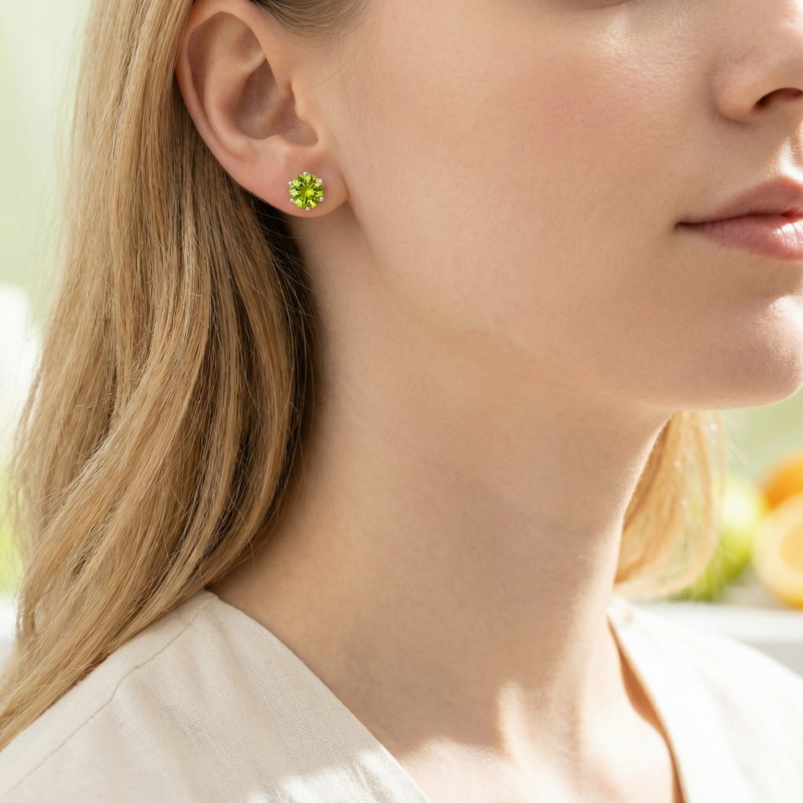 Woman wearing a round-cut simulated peridot stud earring in sterling silver on her ear.